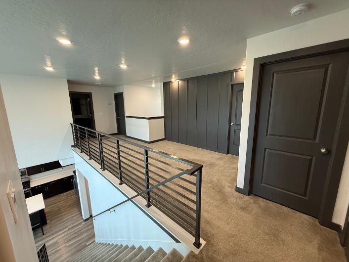 Upper-level landing featuring recessed lighting, dark paneling, and neutral carpet