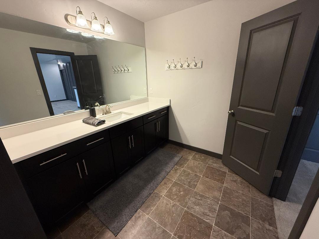 Expansive vanity featuring a white countertop, dual sinks, and dark cabinetry with brushed nickel hardware