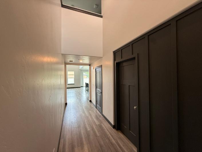 Hallway featuring wood-finish flooring, recessed lighting, and dark paneling with a coordinating door