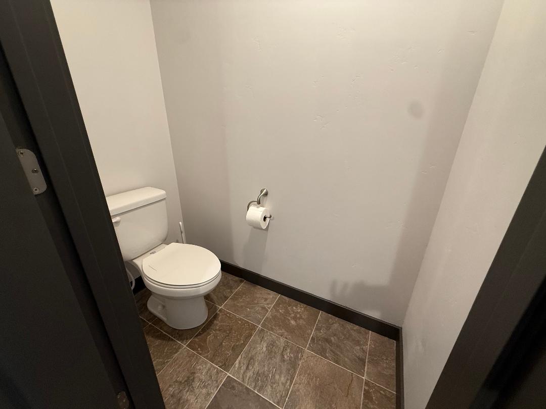 Master bathroom featuring a white toilet, neutral wall color, dark baseboards, and patterned floor tiles