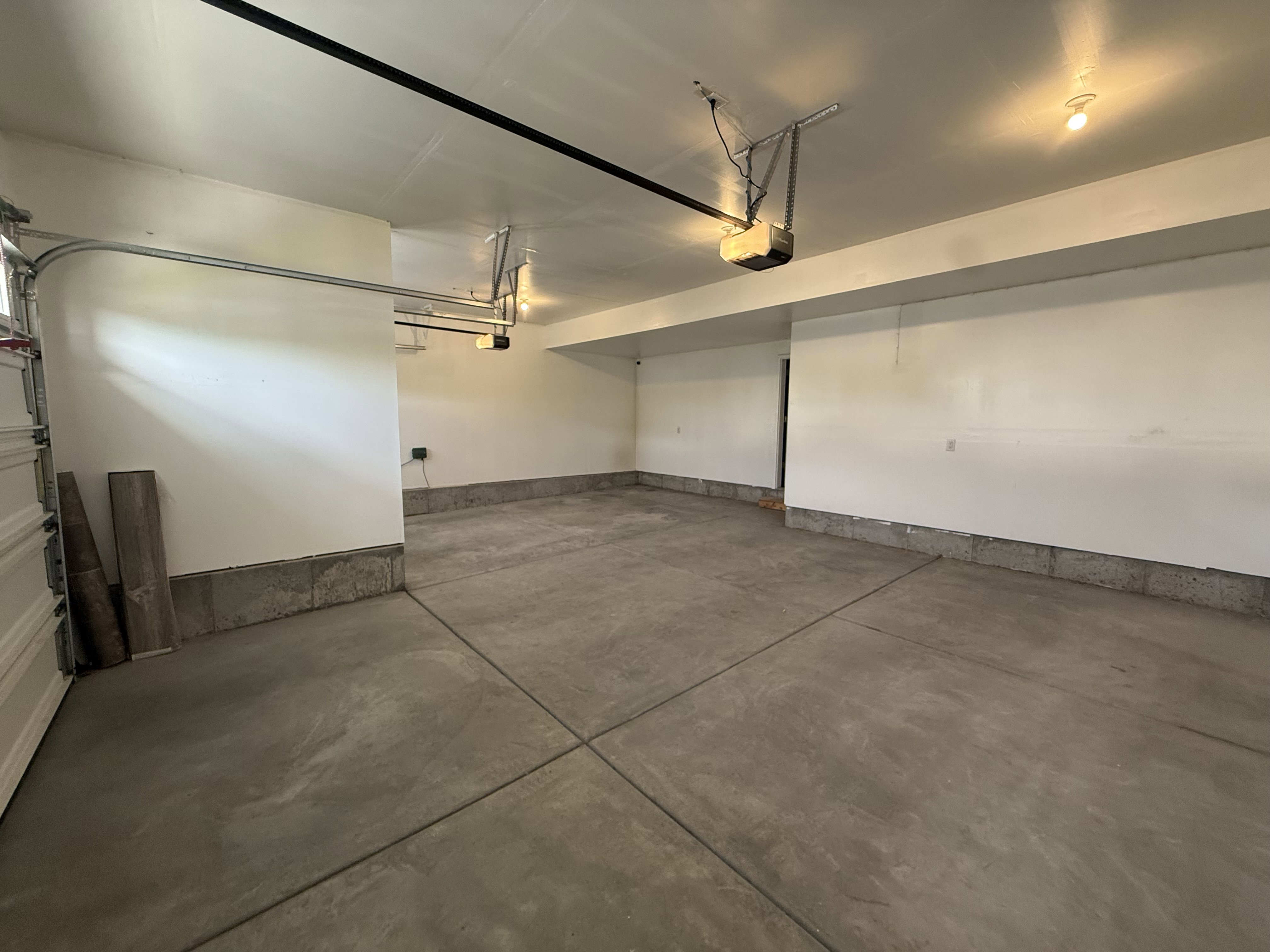 Spacious garage featuring a concrete floor, painted white walls, and built-in garage door openers