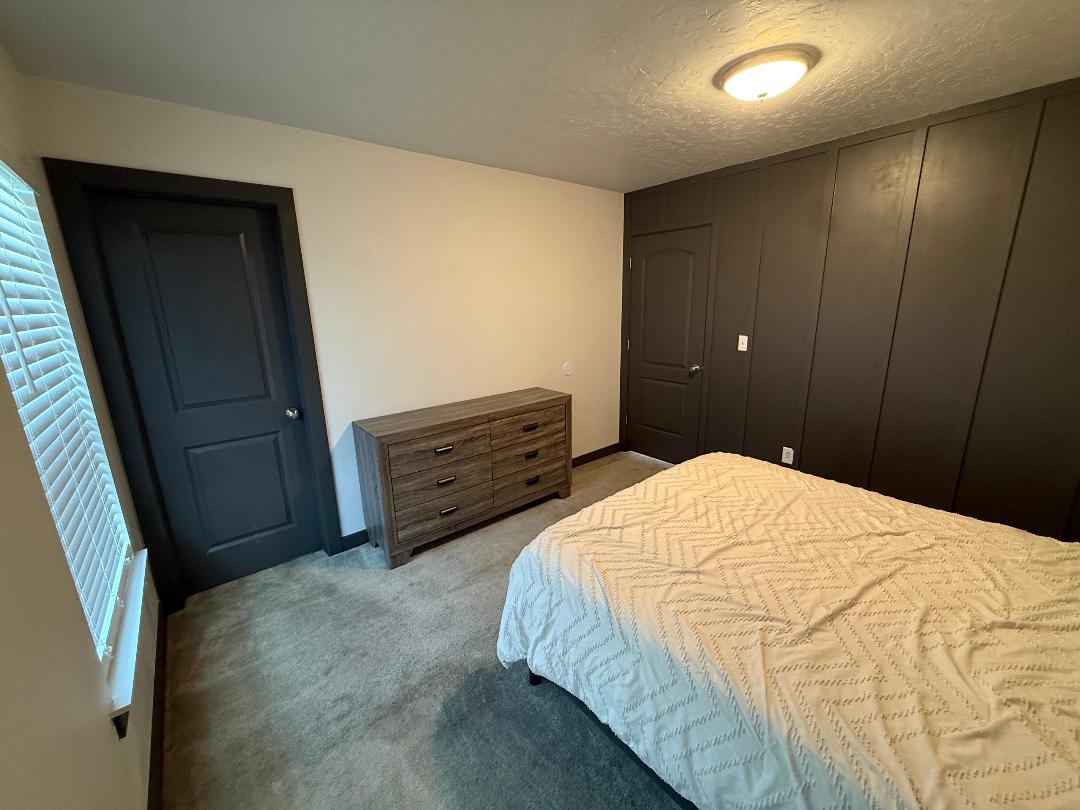 Bedroom featuring a dark accent wall with panel detailing, light neutral walls, and a textured ceiling