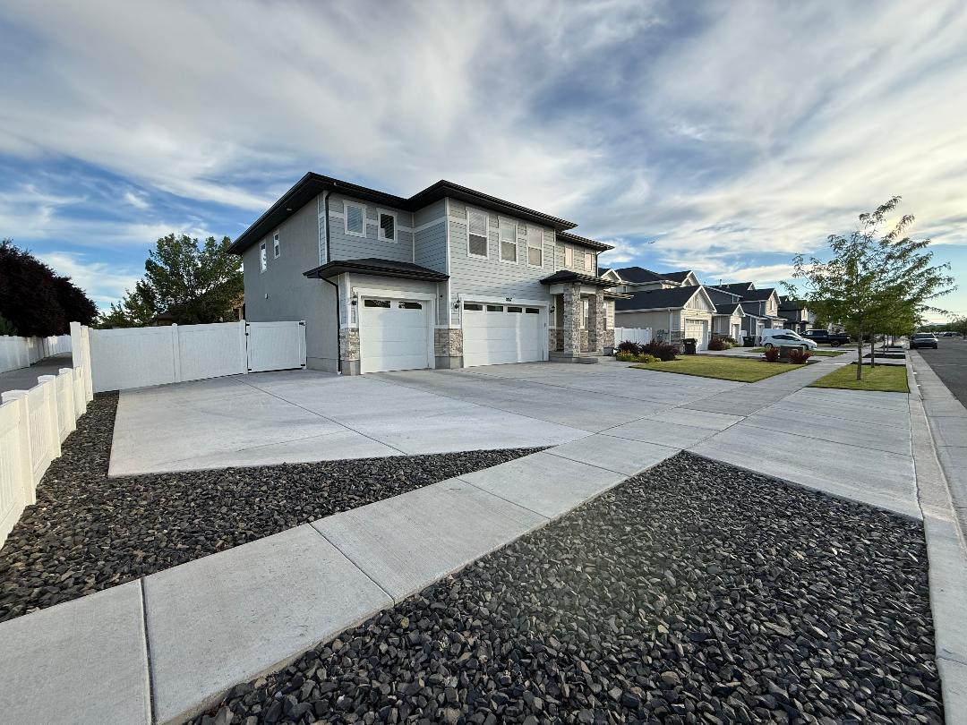 Two-story residence featuring light gray siding, stone accents, and a dark roof