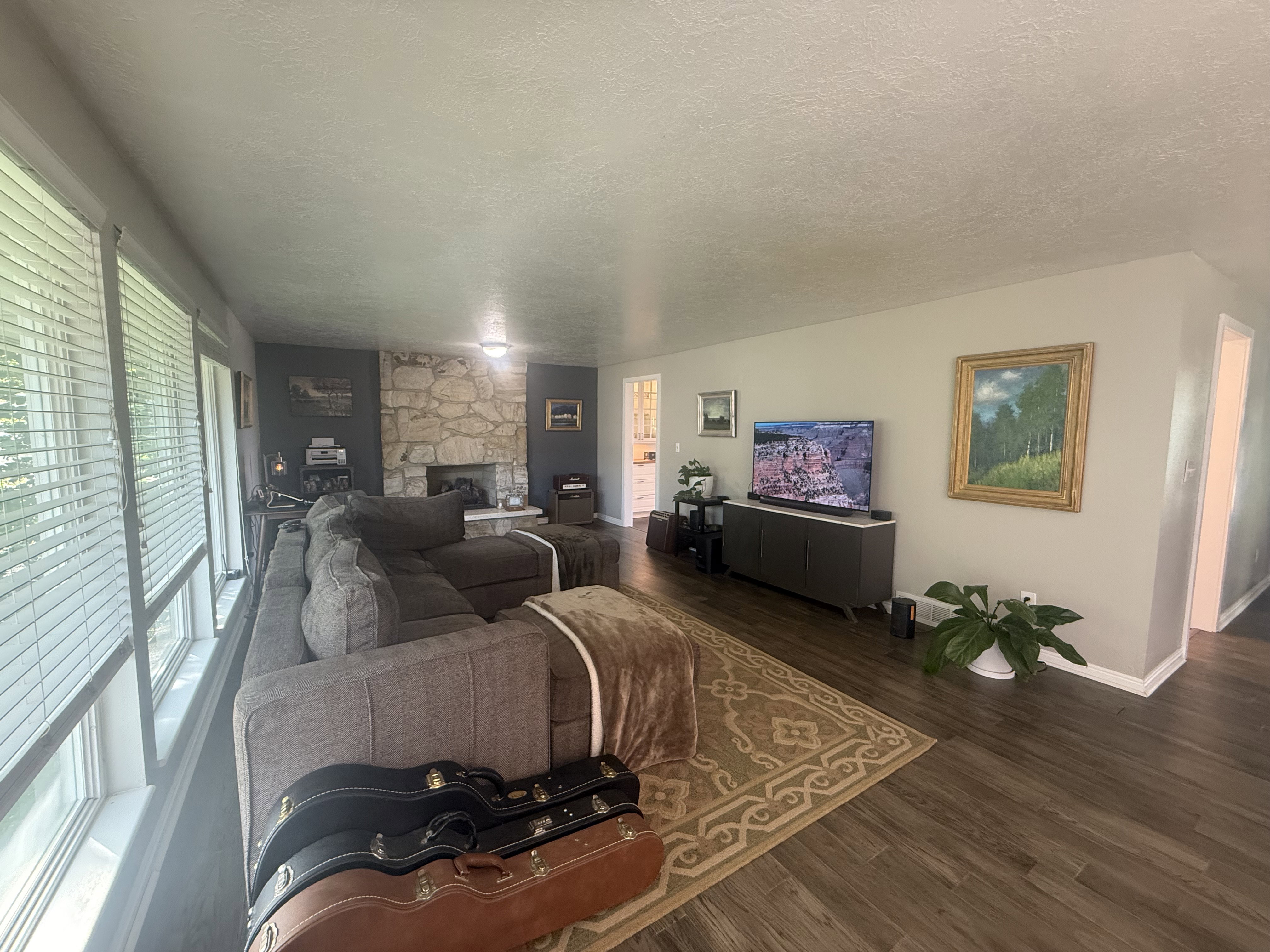Spacious living area featuring a stone-clad fireplace and wood-finish flooring