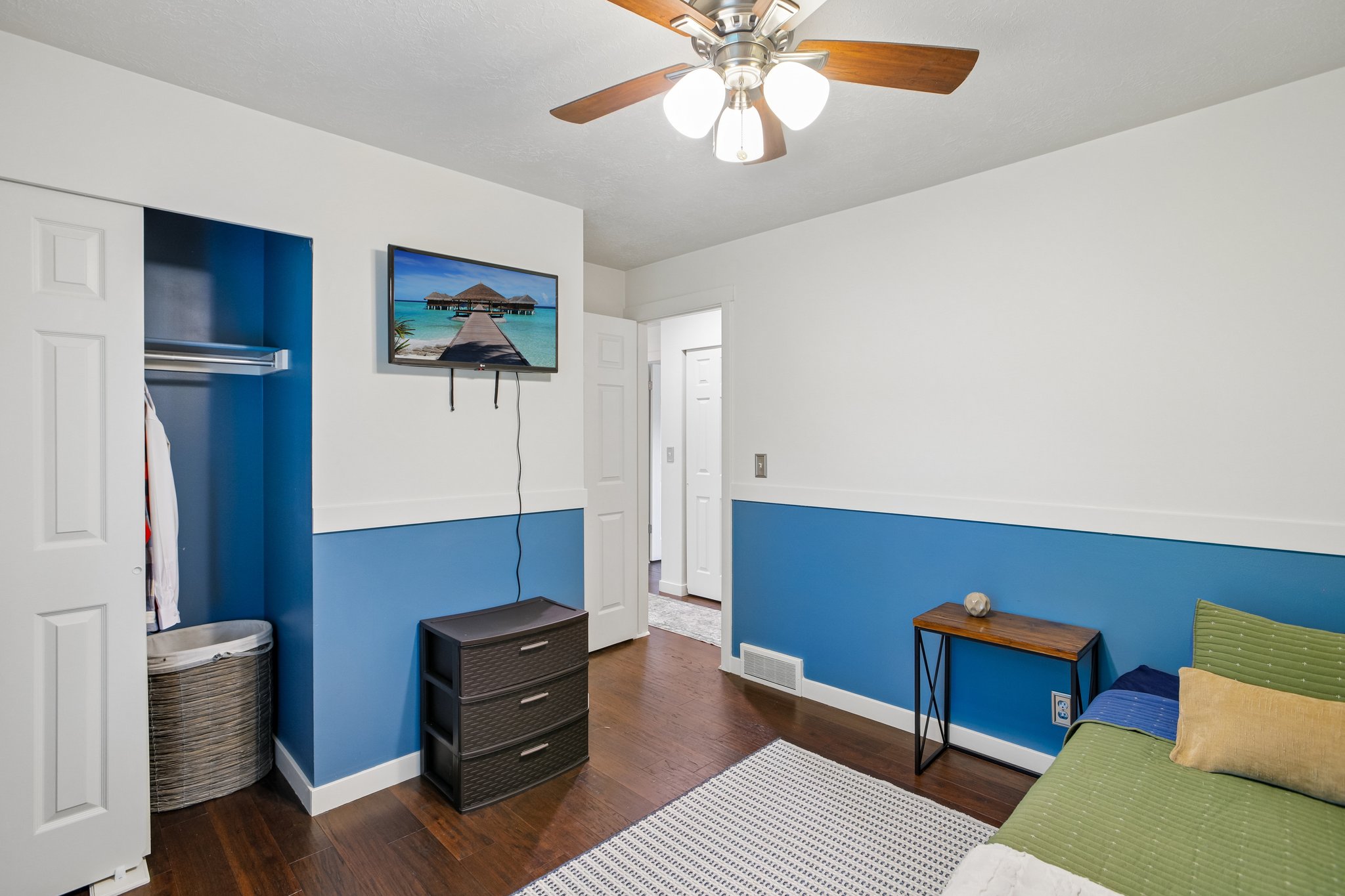 Interior room featuring wood-finish flooring, two-tone wall paint, and a ceiling fan with integrated lighting