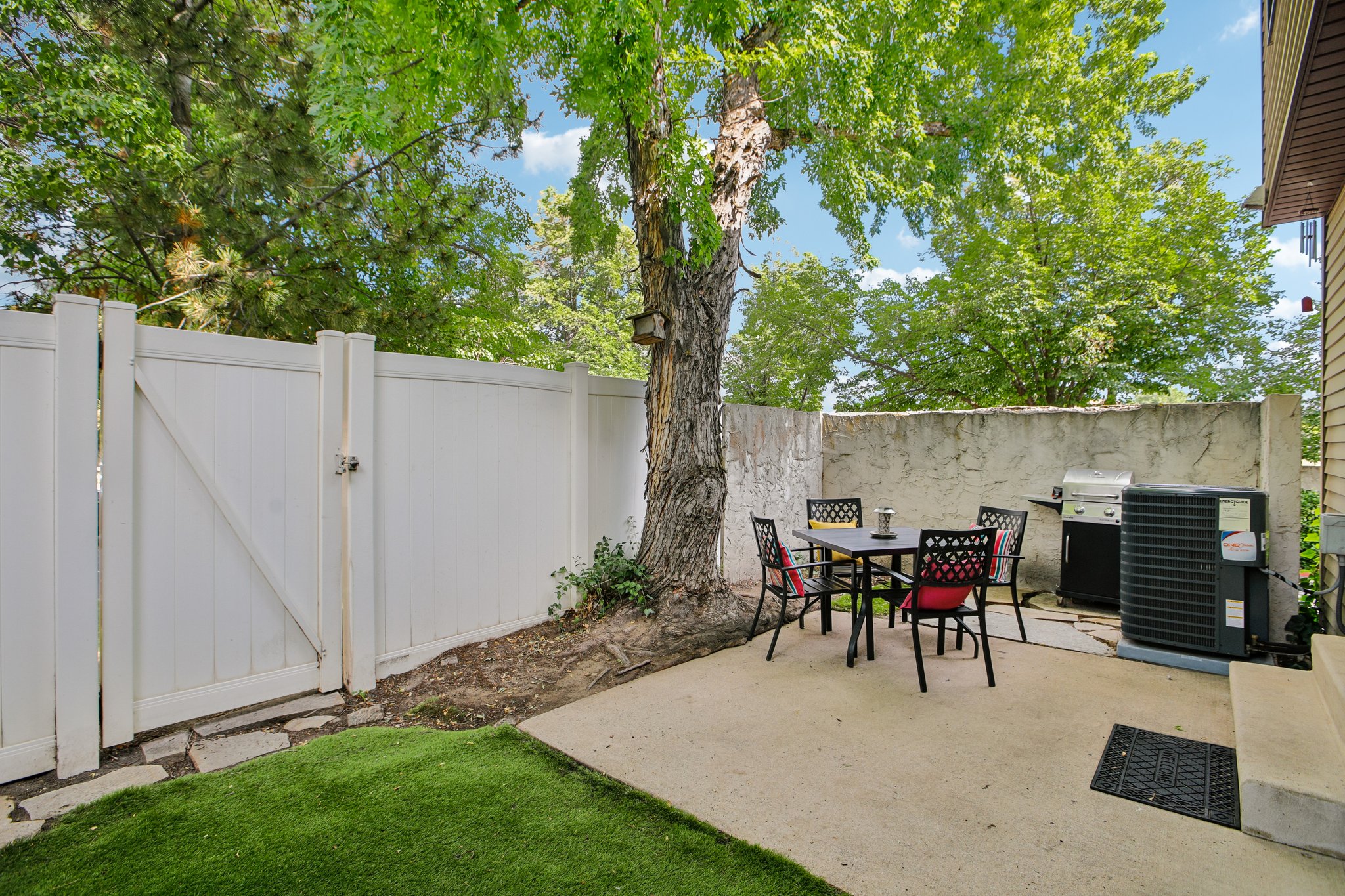 Private patio area featuring a concrete surface, a partial privacy wall, and mature tree