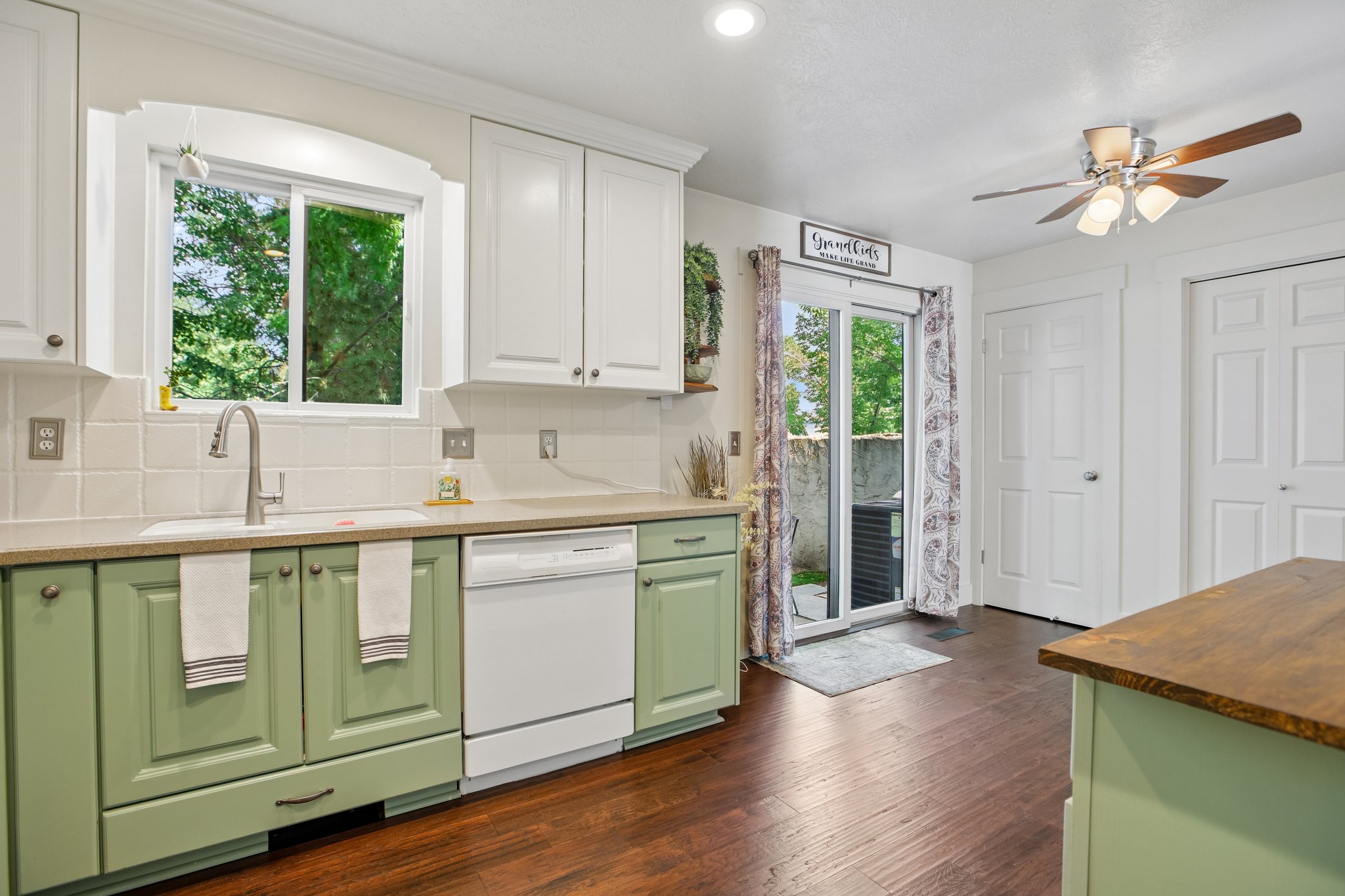 Kitchen featuring two-tone cabinetry with white upper and green lower cabinets, a white tile backsplash, and a contemporary stainless steel faucet