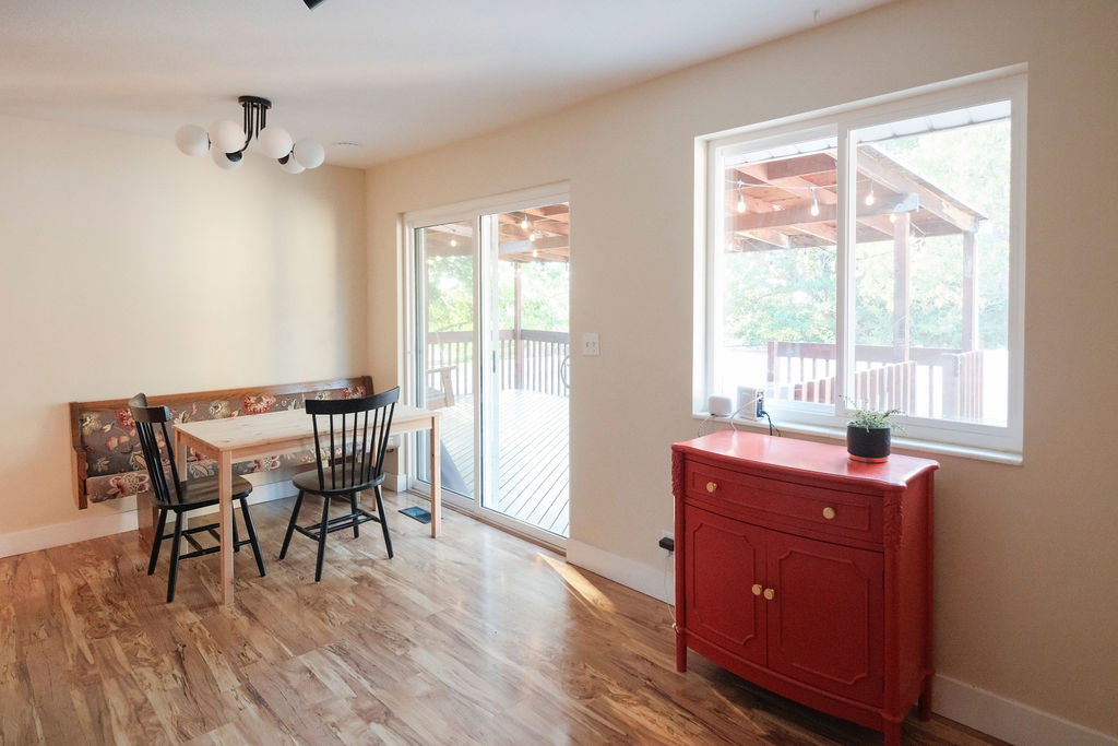Spacious room featuring wood-finish flooring, a contemporary ceiling light fixture, and a built-in upholstered bench