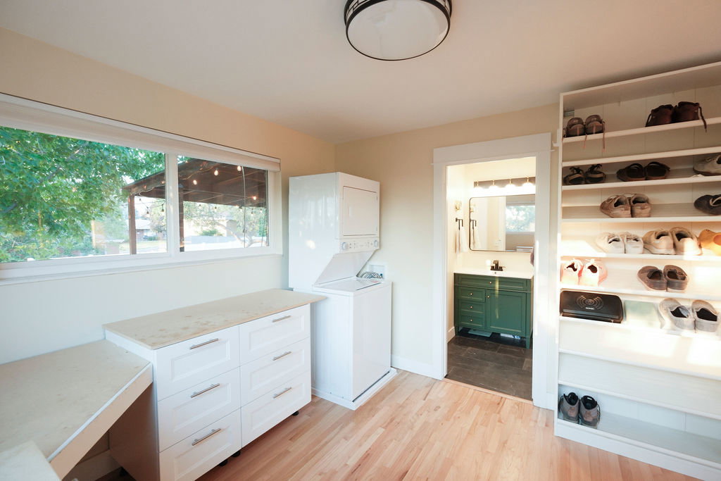 Laundry room featuring hardwood-finish flooring, a stacked washer and dryer, and a built-in storage unit