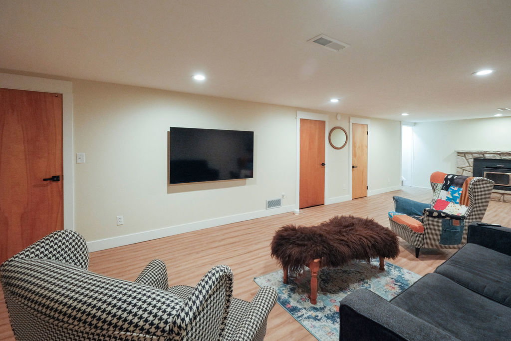 Spacious living area featuring wood-finish flooring, recessed lighting, and a stone fireplace