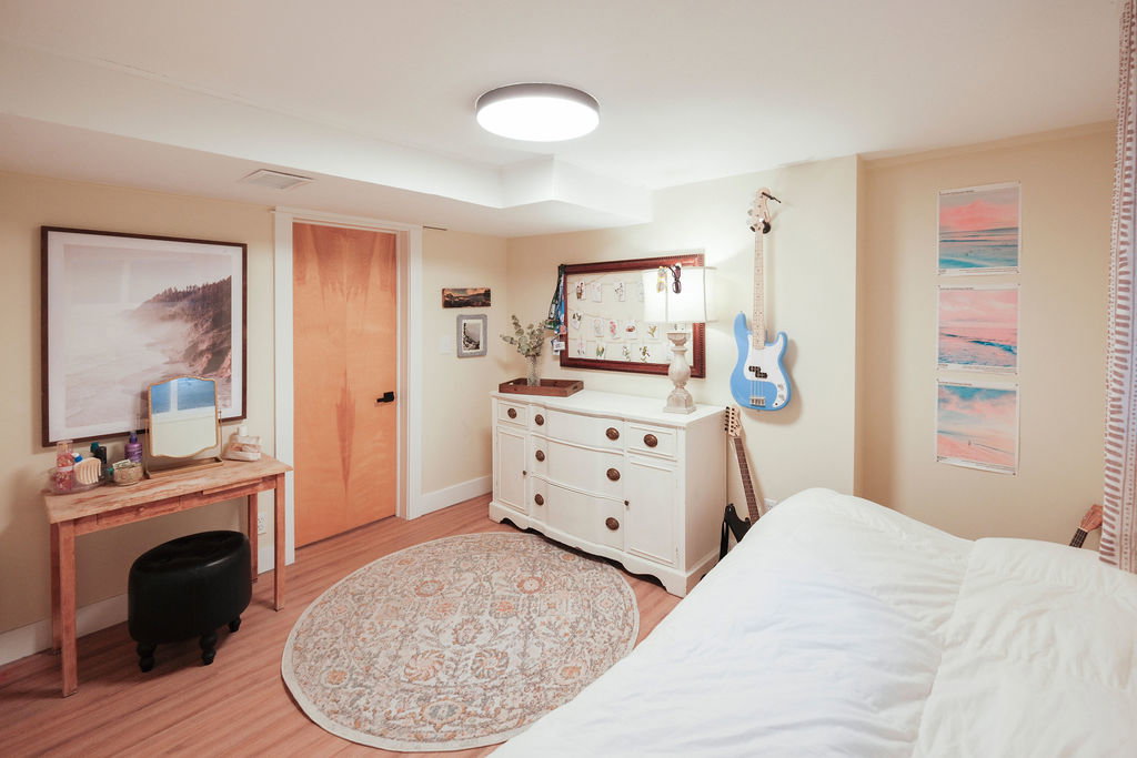 Interior room featuring light-toned walls, wood-finish flooring, a flush-mount ceiling light fixture, and white baseboards