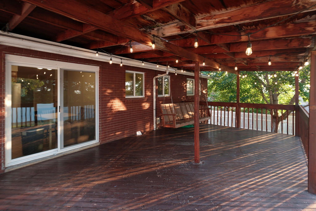 Expansive covered wood deck featuring string lighting and a wood railing