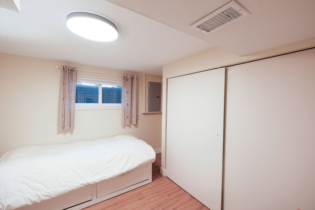 Bedroom featuring wood-finish flooring, a contemporary flush-mount ceiling light, and a window with a sill