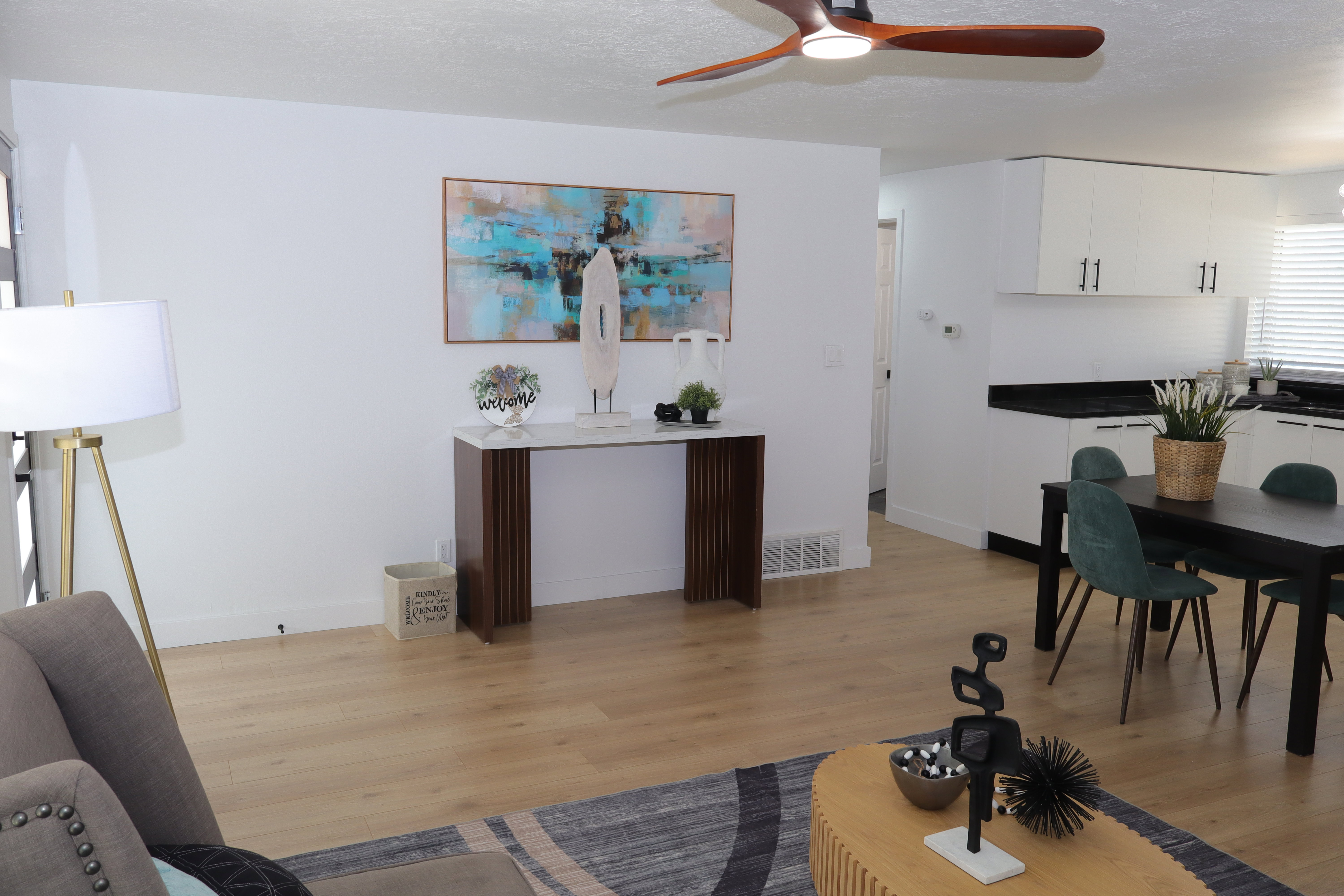 Open concept living area featuring light wood-finish flooring, white walls, and a contemporary ceiling fan