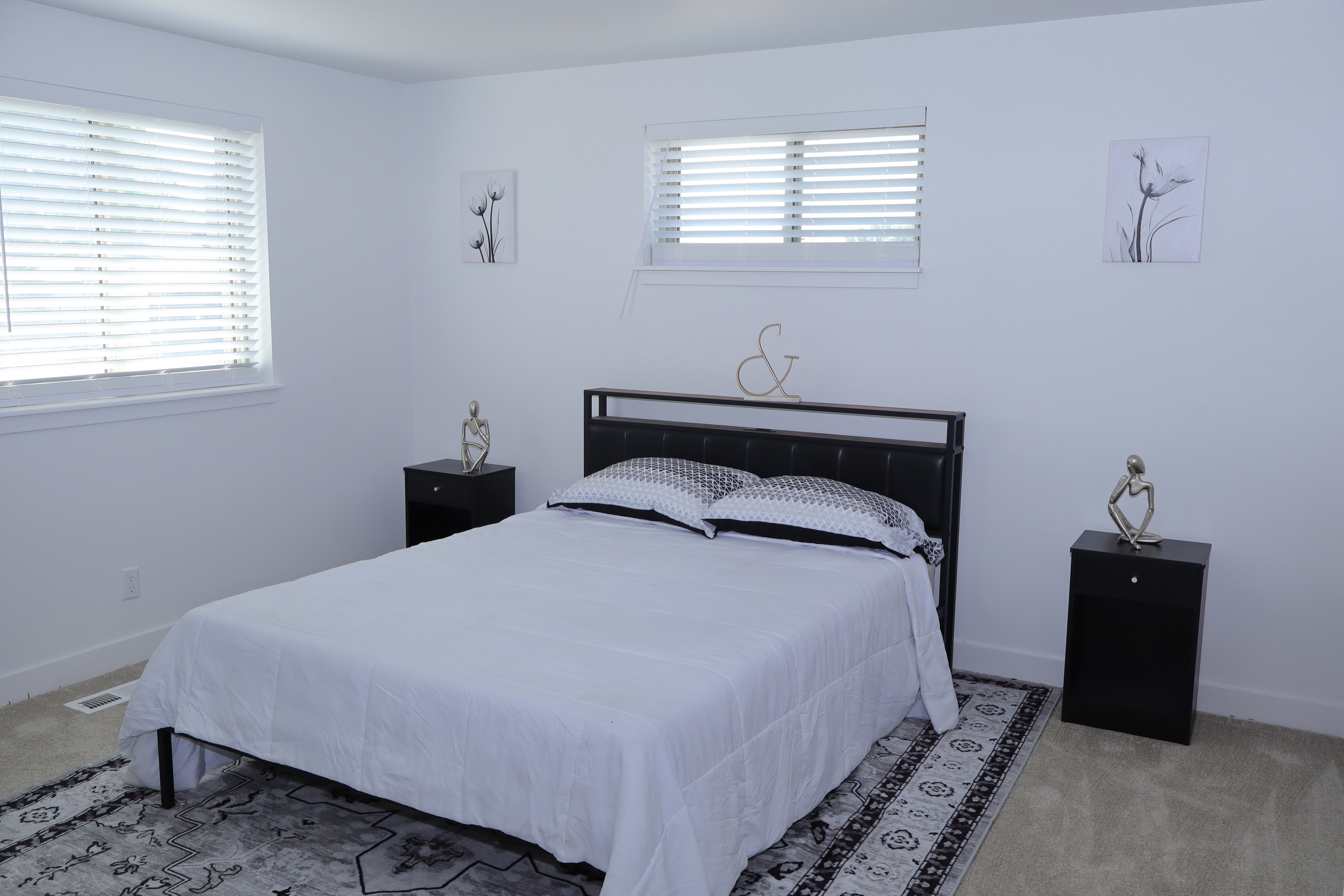 Spacious room featuring neutral carpeting, white walls, two windows with blinds, and white trim