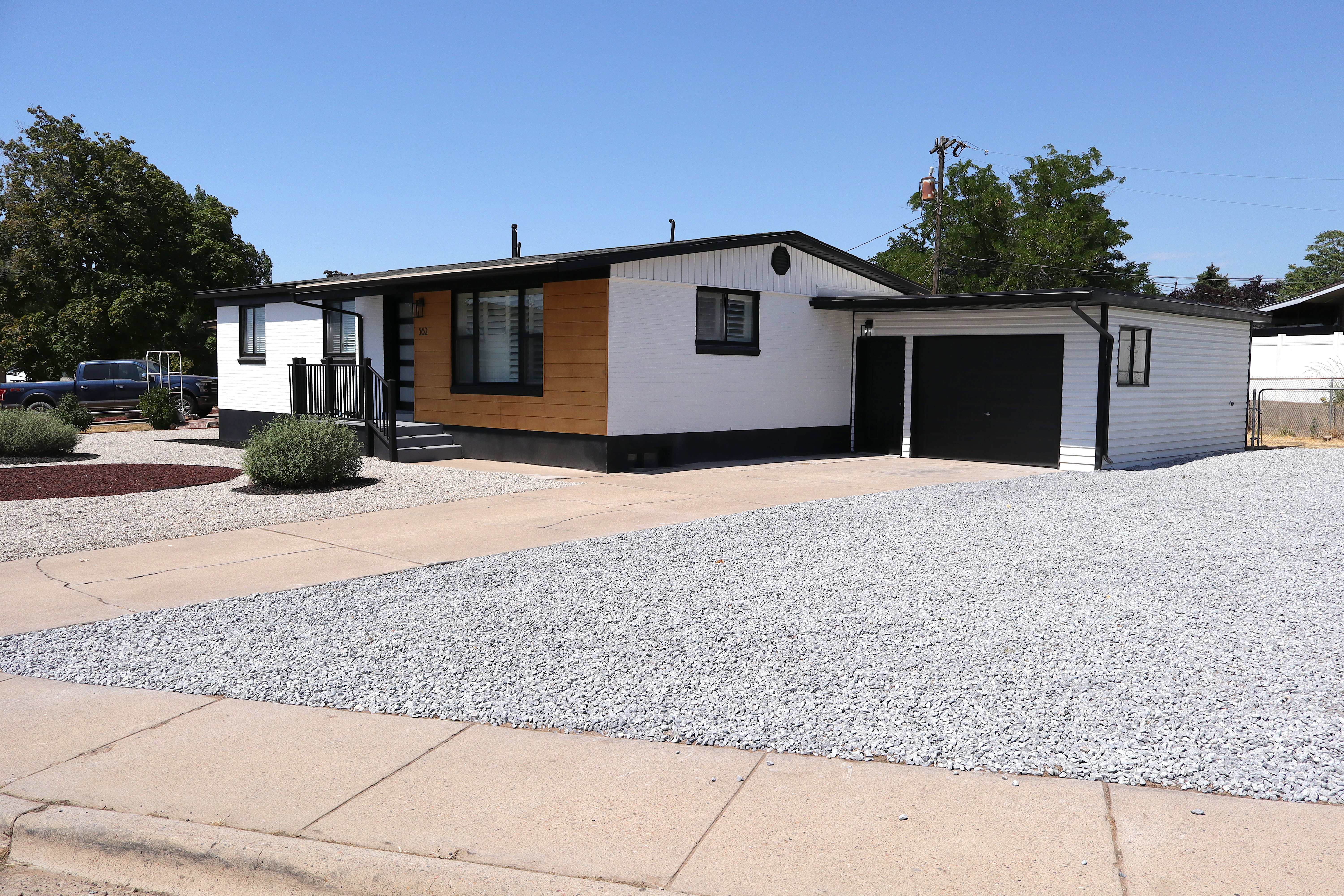 Contemporary exterior featuring white siding, black trim, and wood-finish accent panels