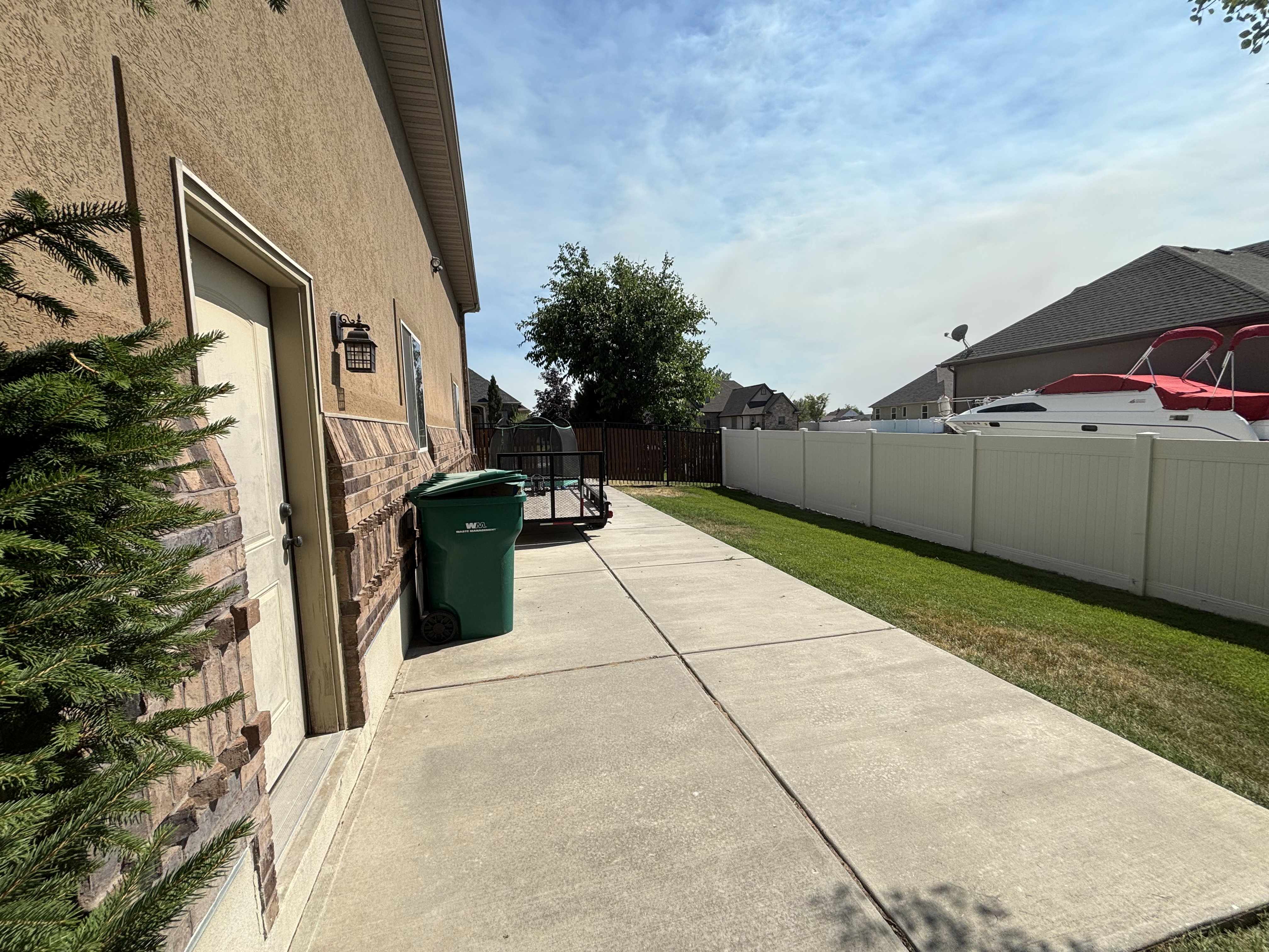 Side yard concrete pathway with a stucco exterior and brick wainscoting