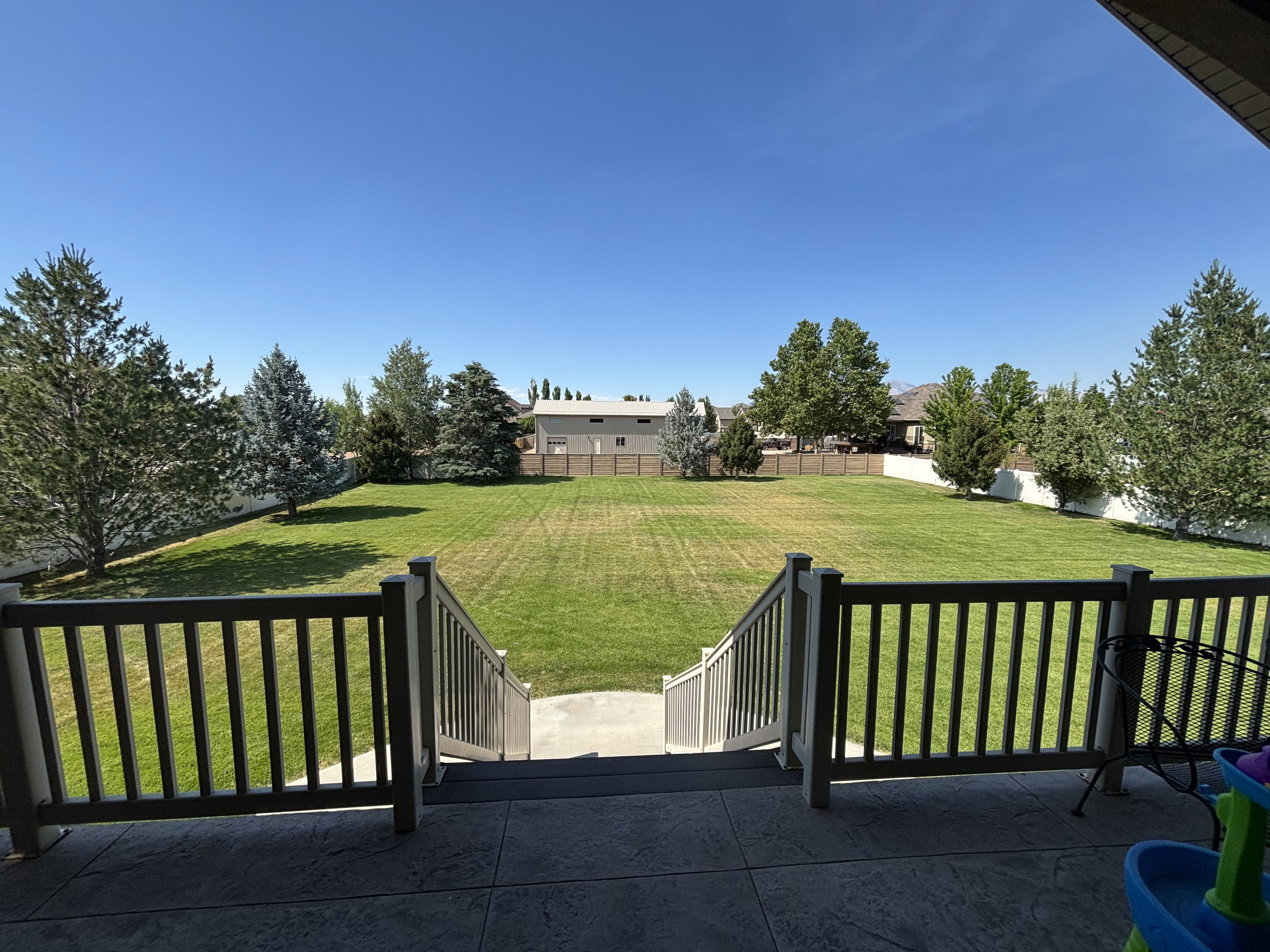 Expansive backyard featuring a manicured lawn, established trees, and a privacy fence