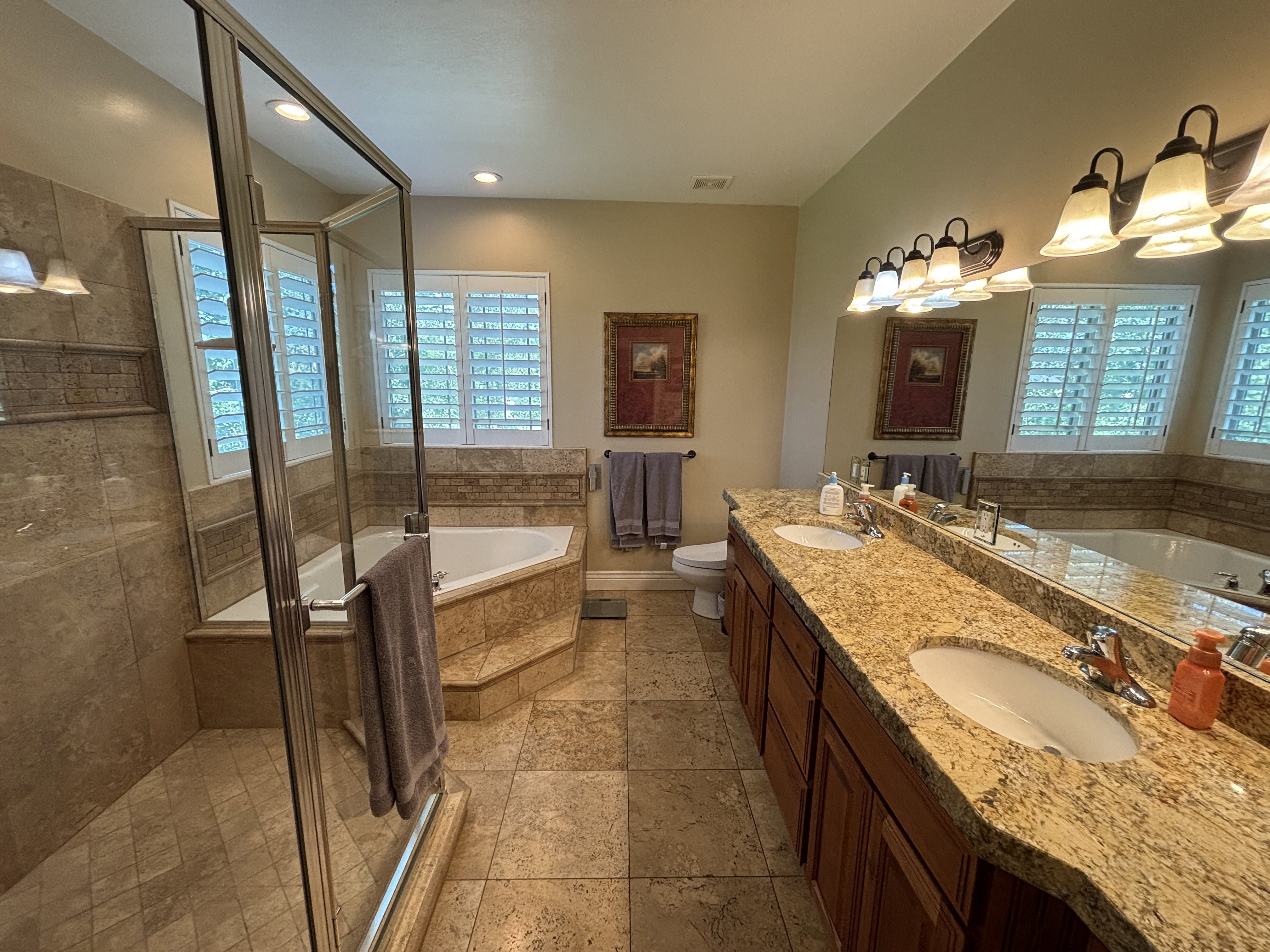 Bathroom featuring a dual vanity with a speckled countertop, integrated sinks, and wood cabinetry