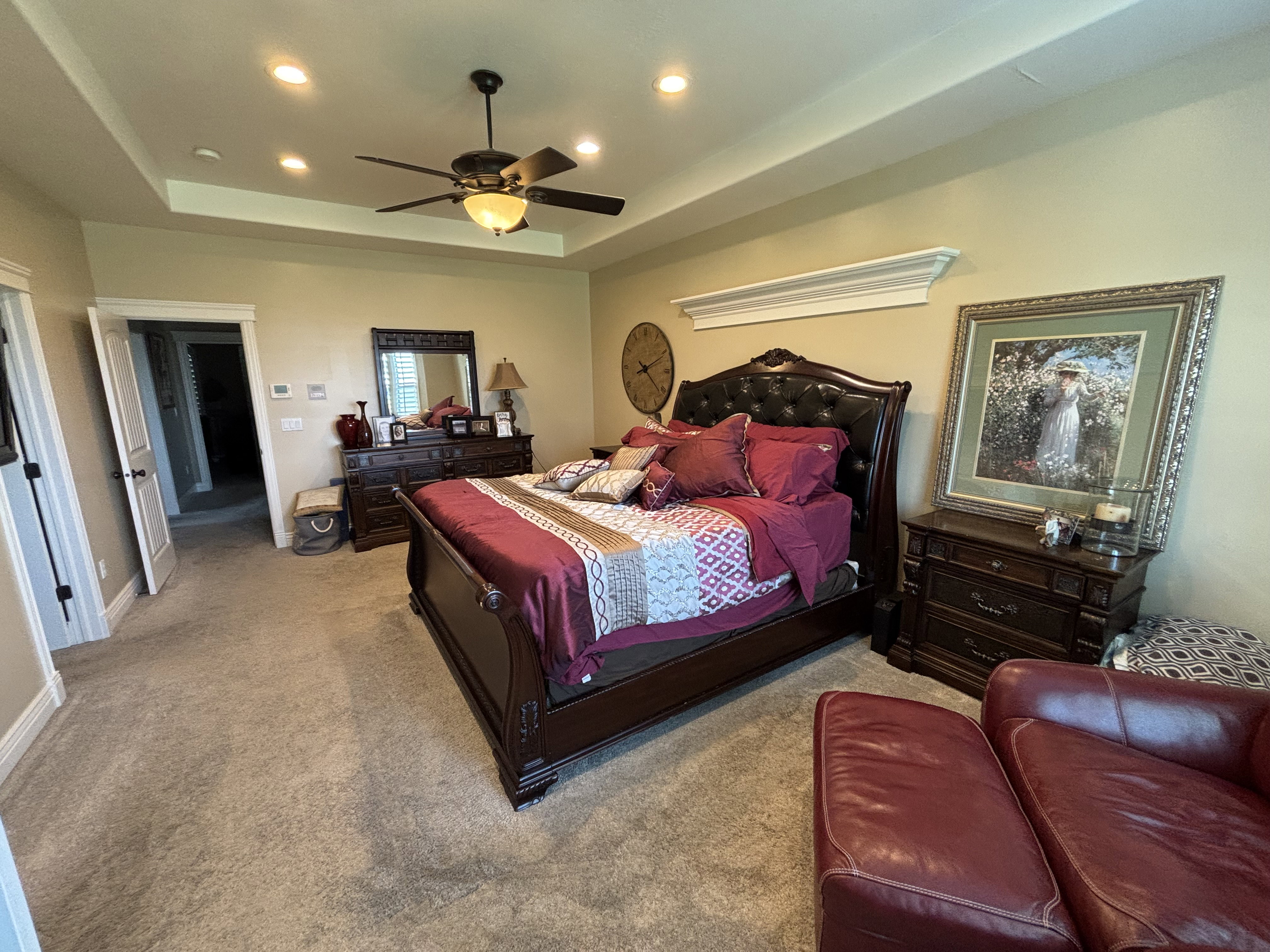 Spacious room featuring a tiered tray ceiling with recessed lighting and a ceiling fan