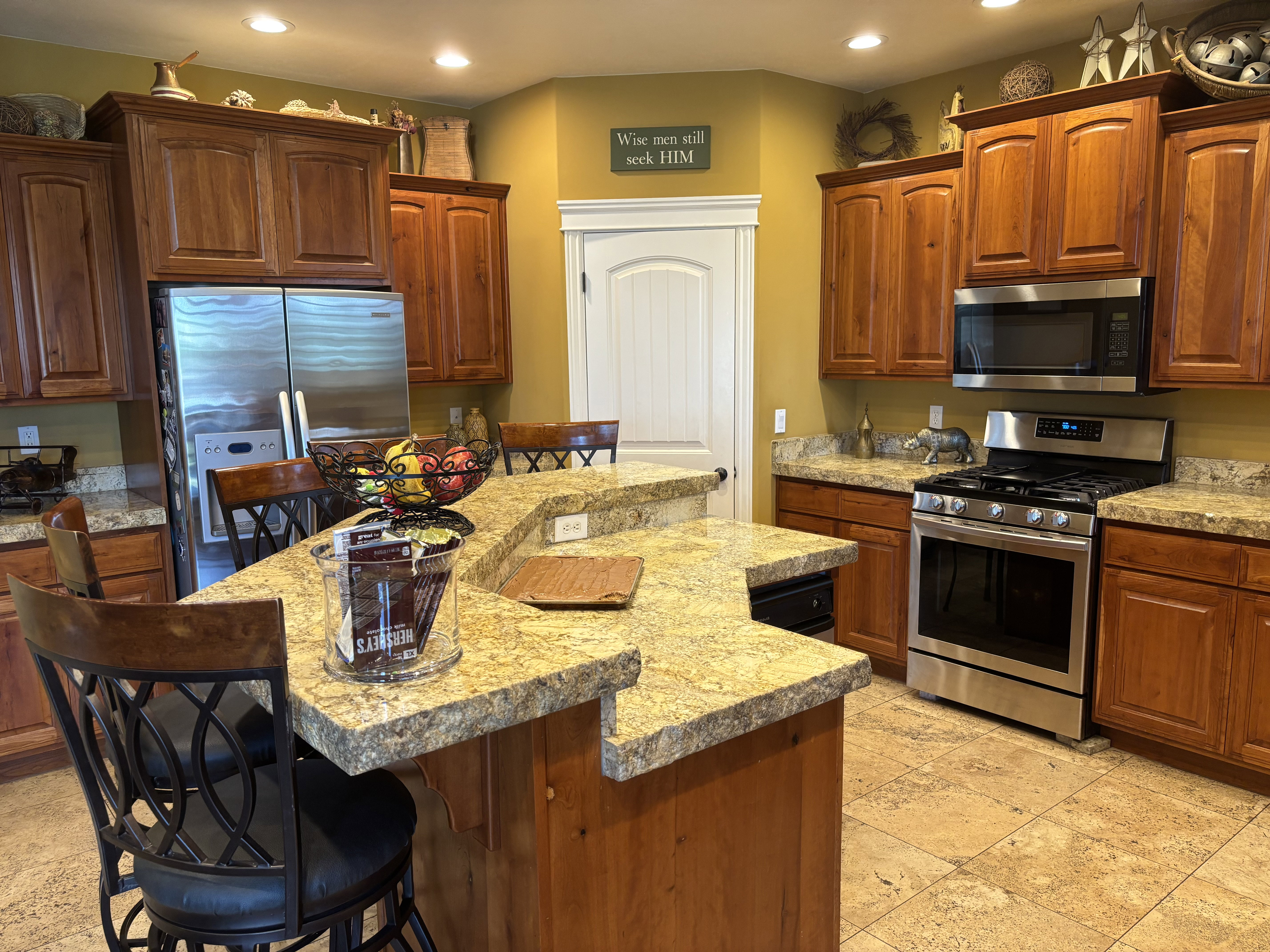 Kitchen featuring a multi-level island with stone countertops, integrated stainless steel appliances, extensive wood cabinetry, and recessed lighting