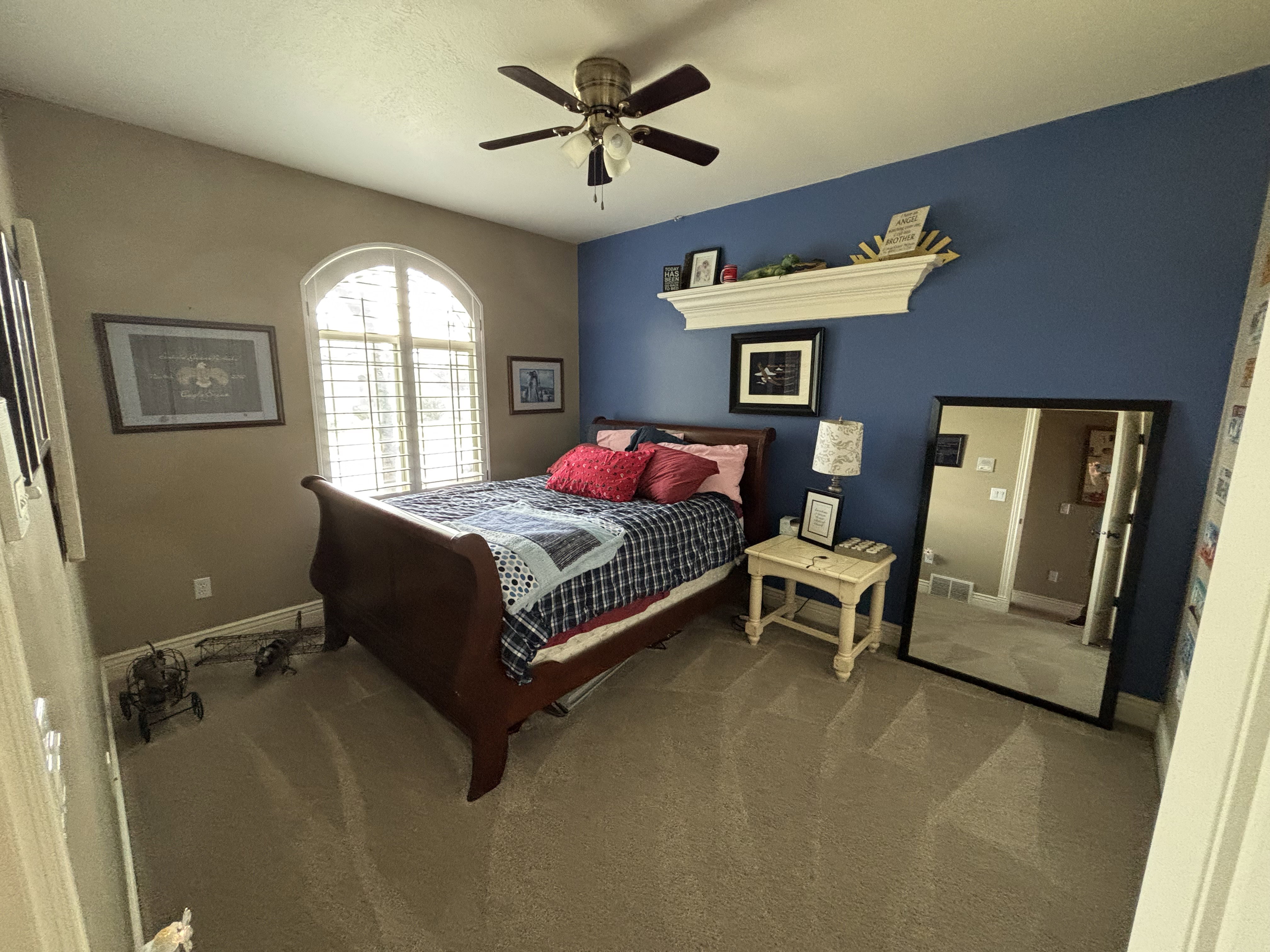 Carpeted interior space featuring an arched window with plantation shutters