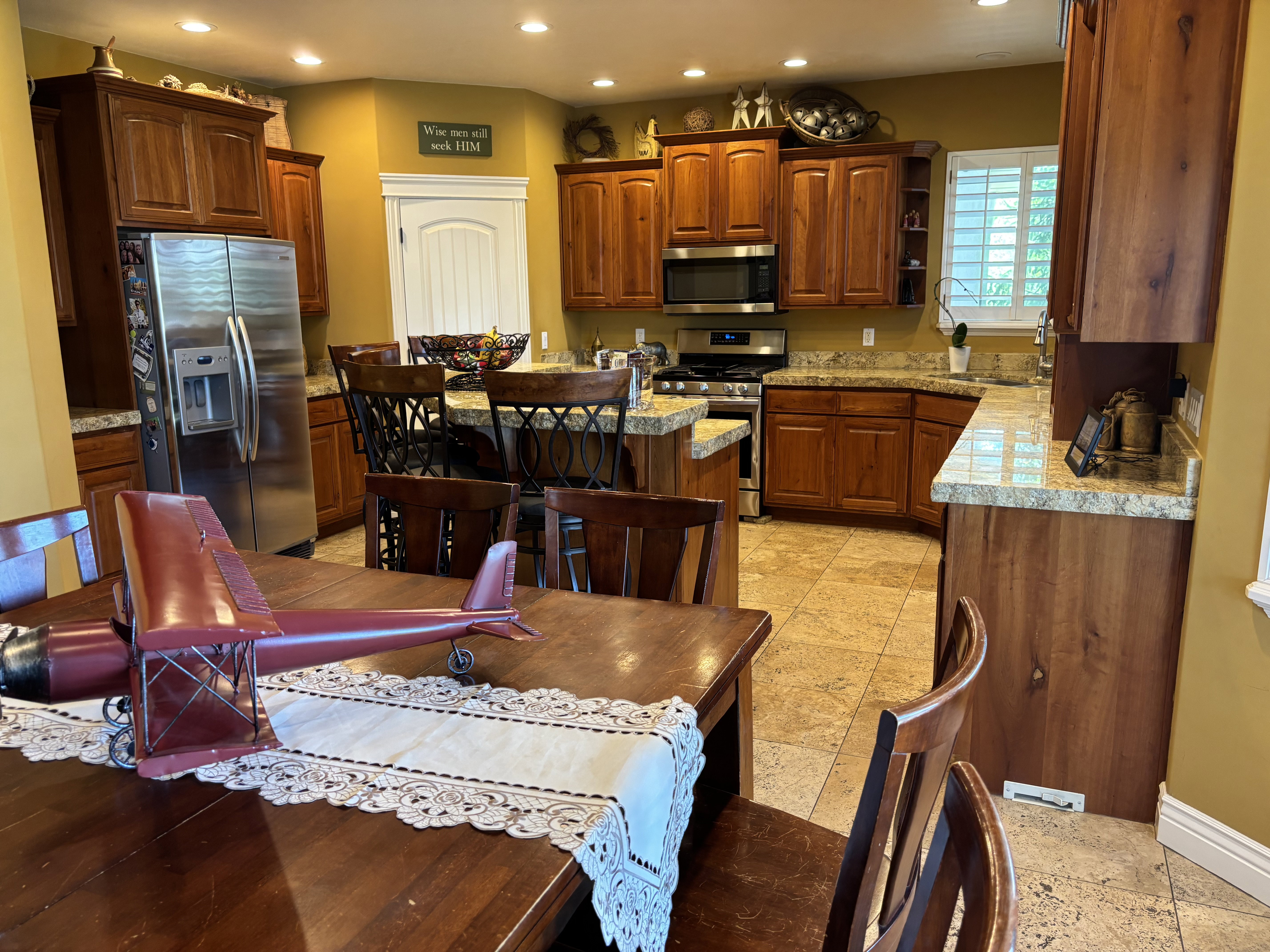 Kitchen featuring wood cabinetry, granite countertops, stainless steel appliances, a center island with seating, and tile flooring