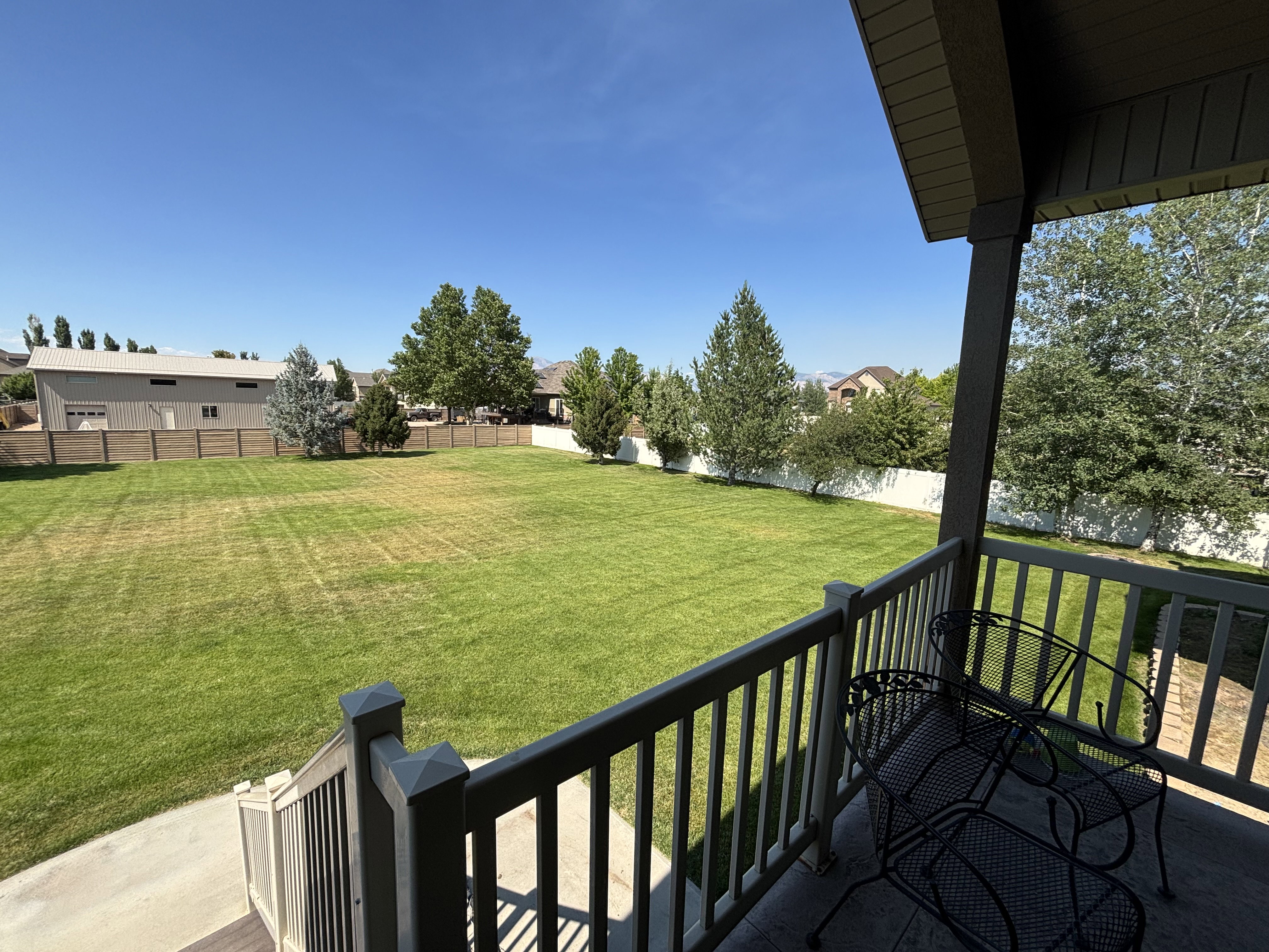 Expansive lawn area with mature trees, surrounded by fencing