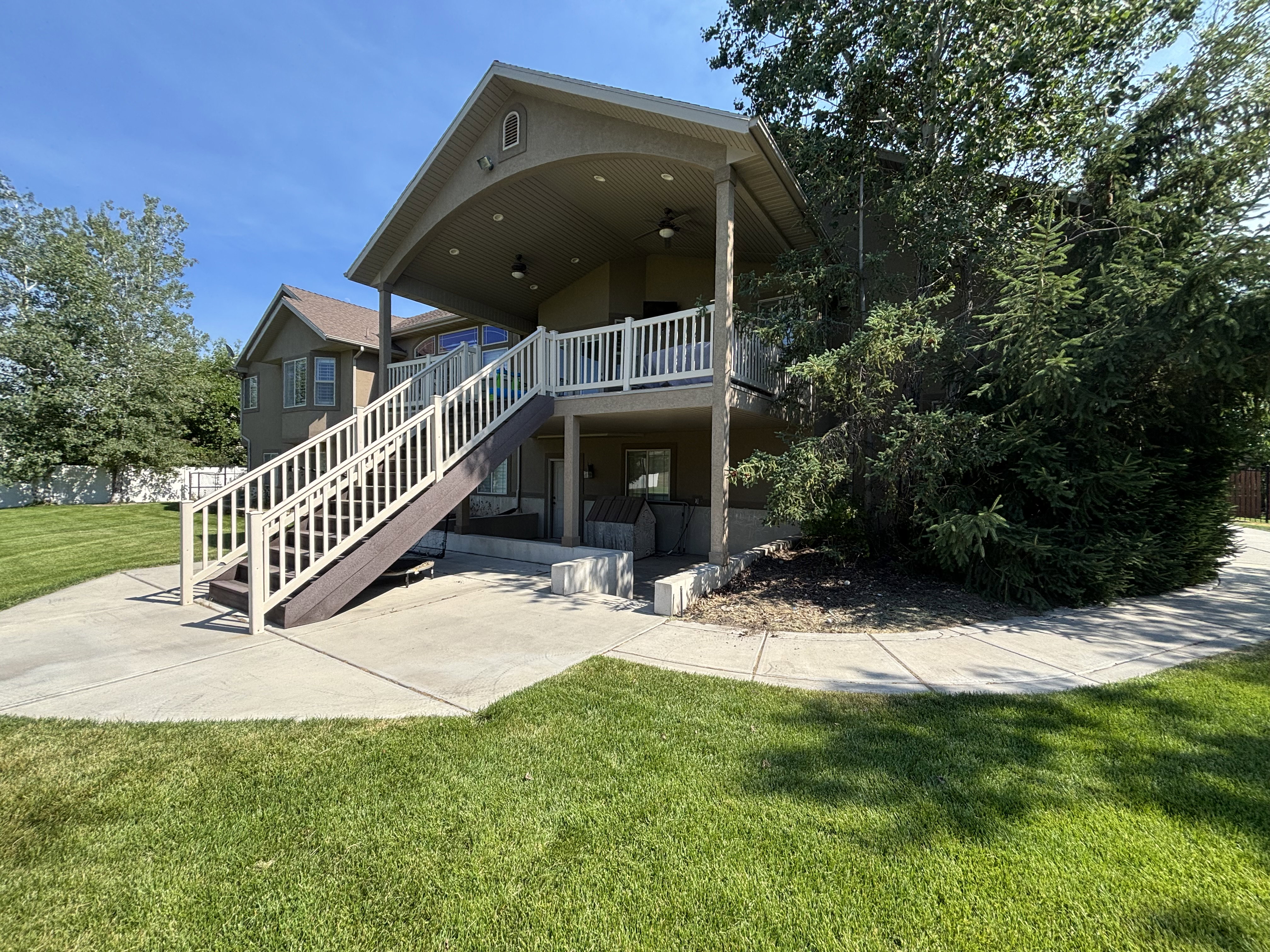 Expansive concrete patio with direct access to a covered upper deck and lower-level outdoor space