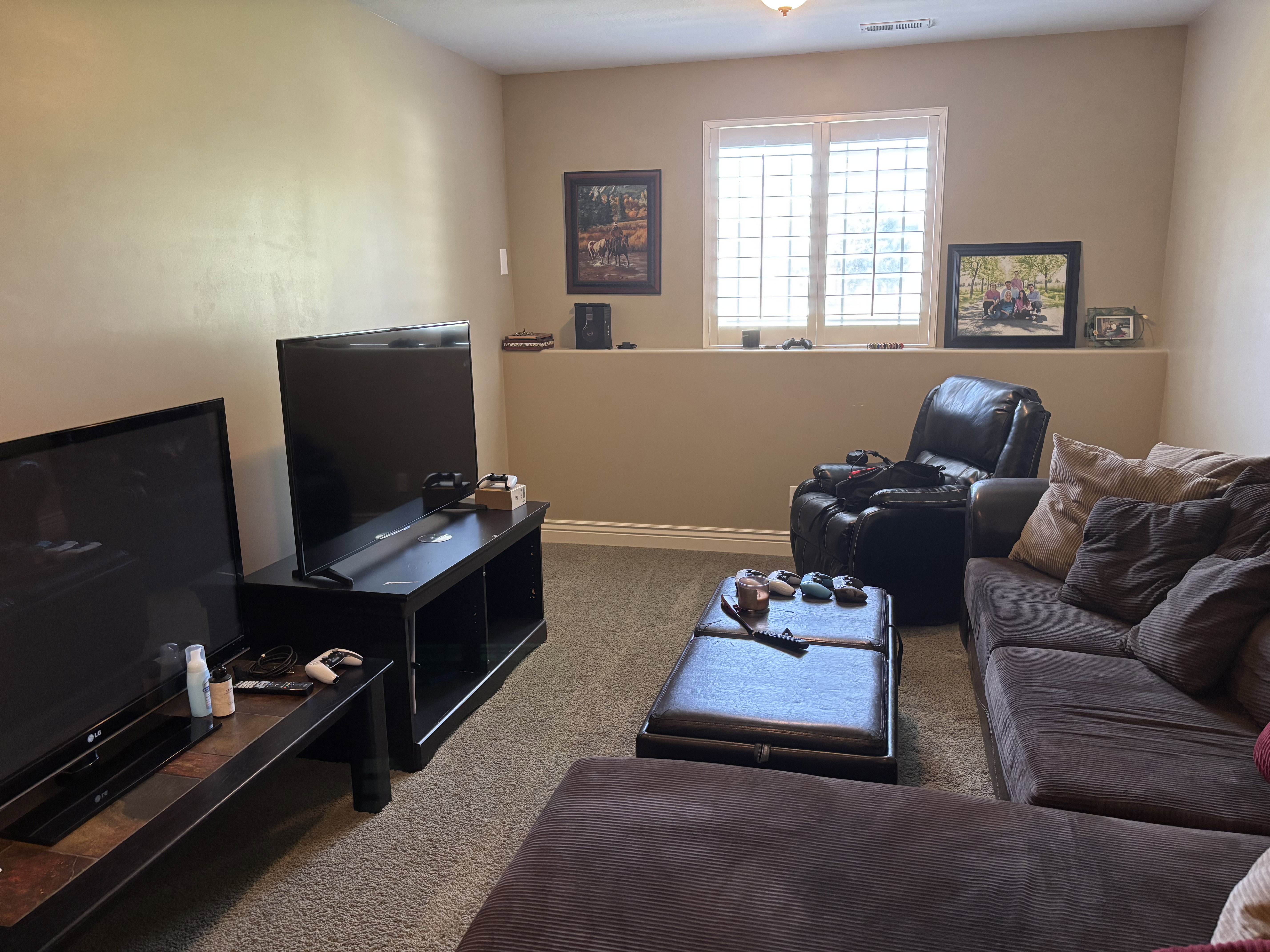 Carpeted room featuring a built-in half-wall and a window with plantation shutters
