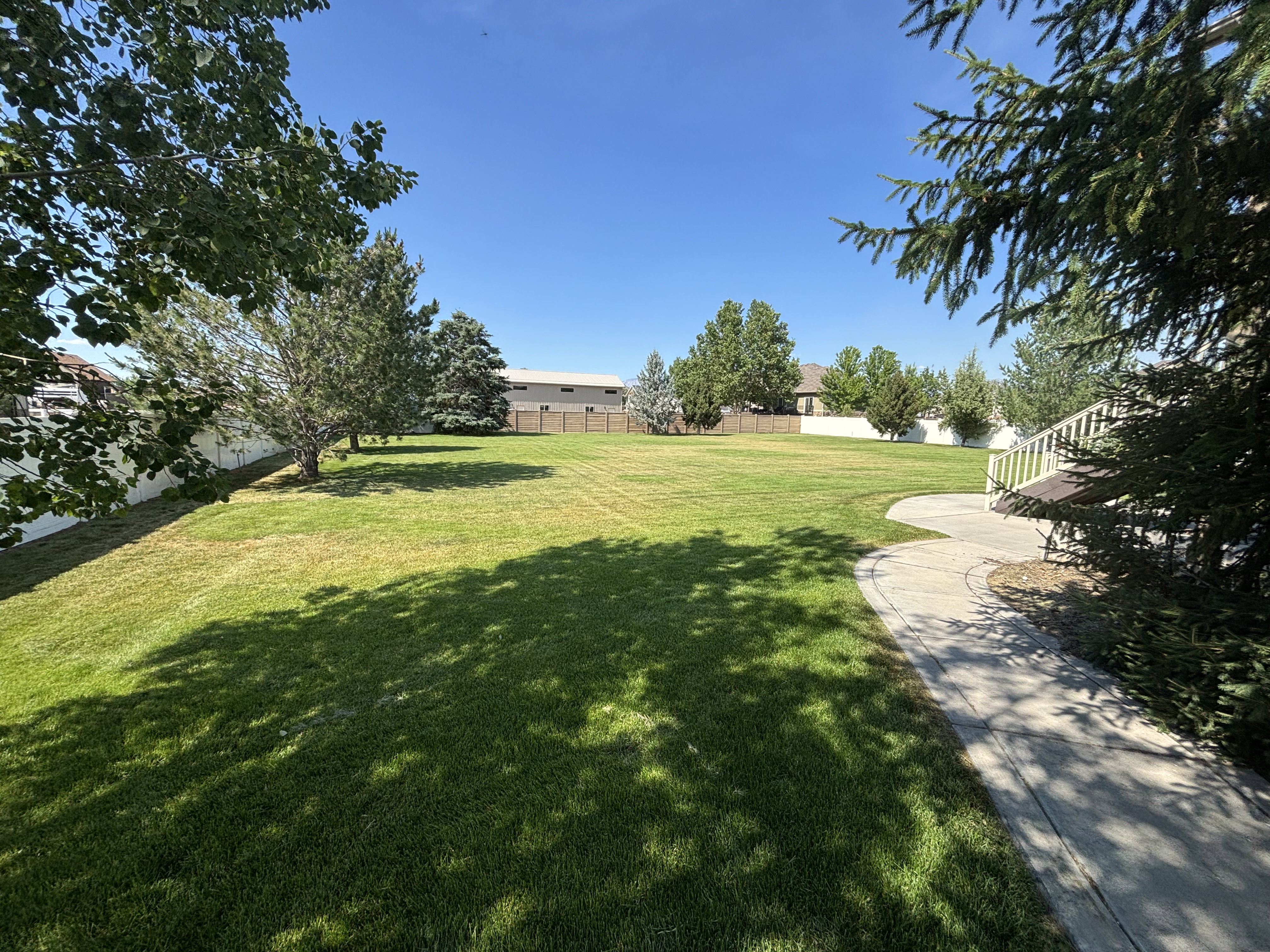 Expansive green lawn with mature trees and a curving paved pathway