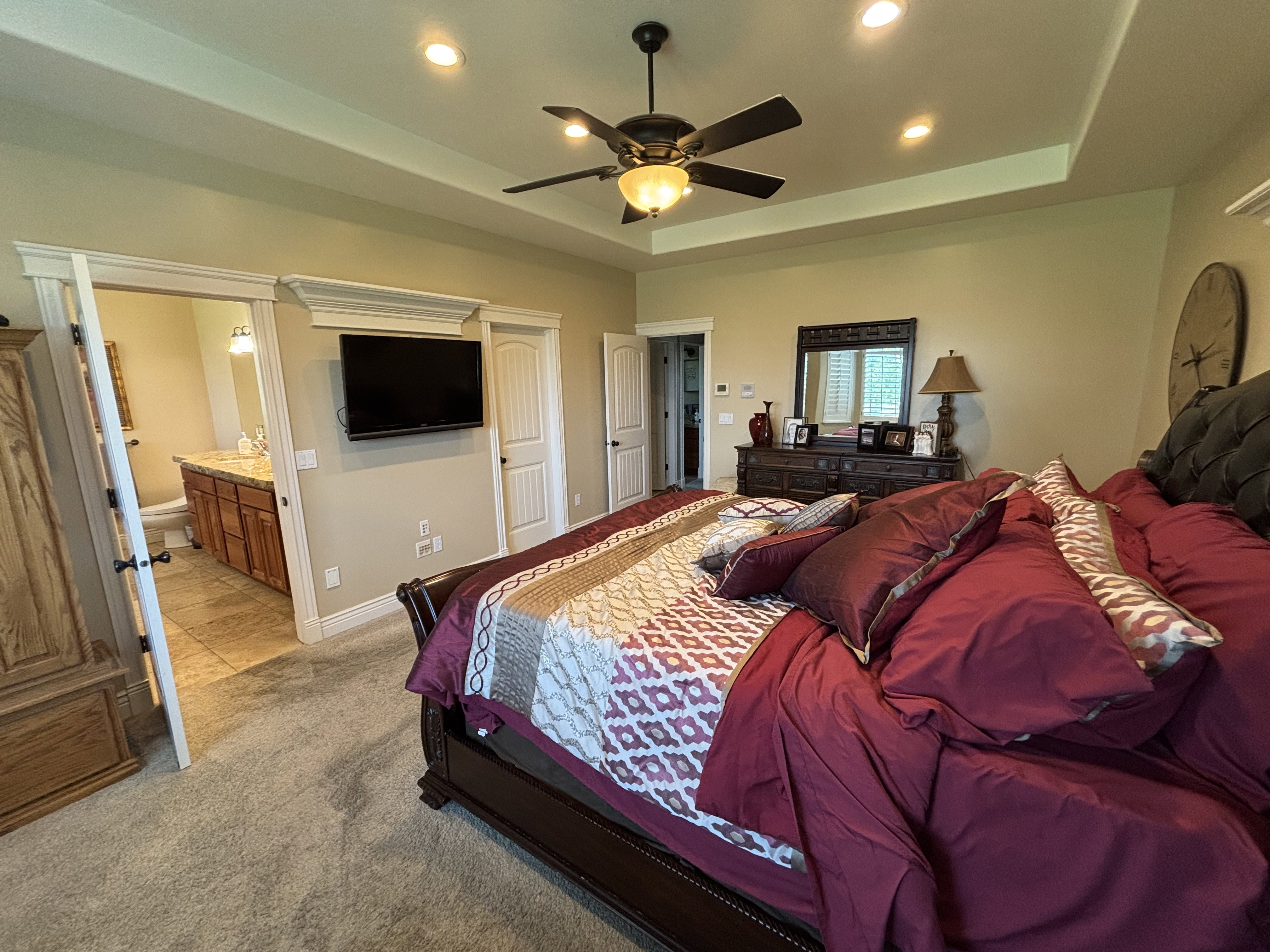 Spacious room featuring tray ceilings with recessed lighting and a ceiling fan