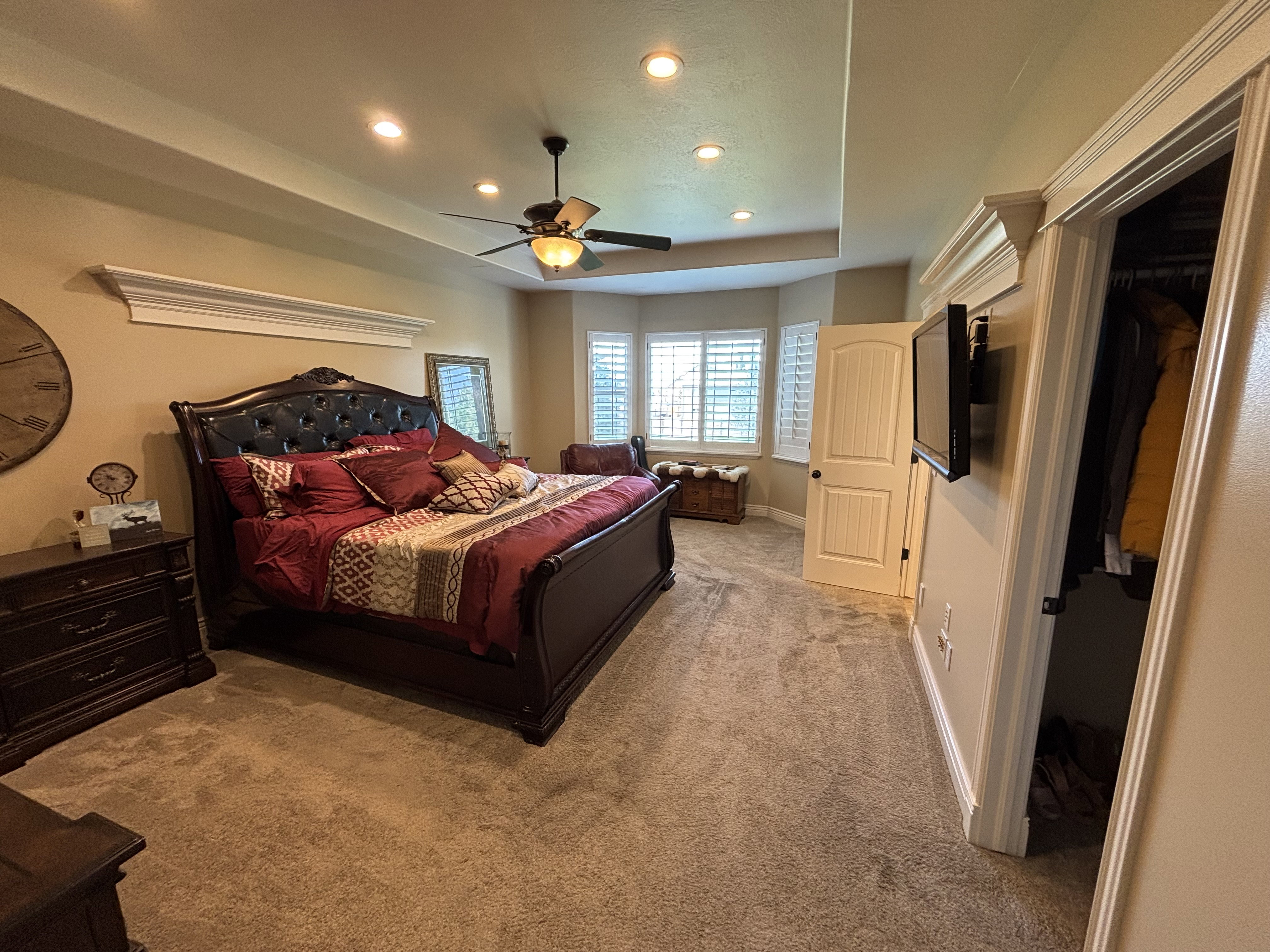 Recessed lighting illuminates the tray ceiling and carpeted flooring