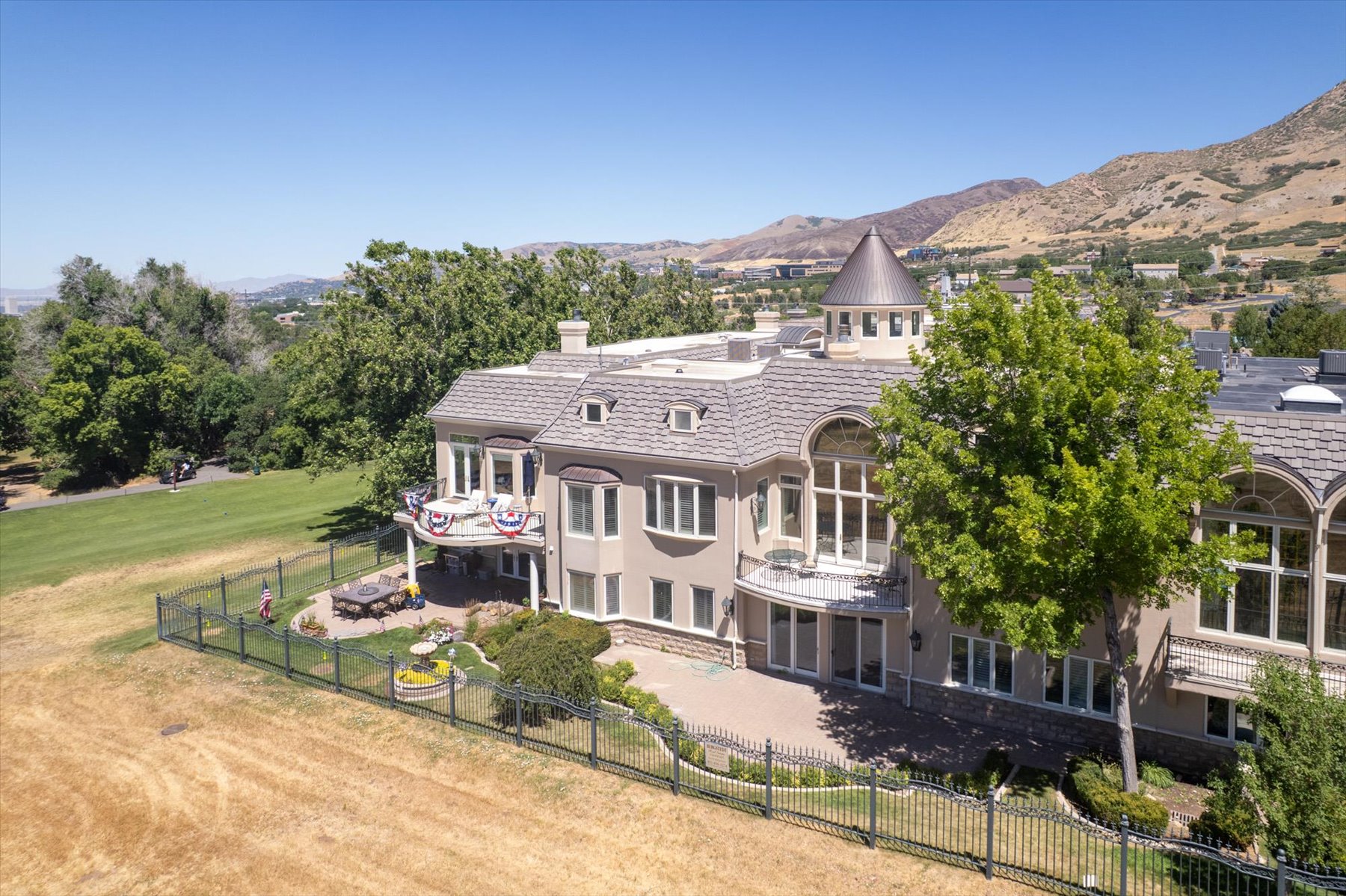 Stately multi-level residence with a prominent turret feature, multiple balconies, and arched windows