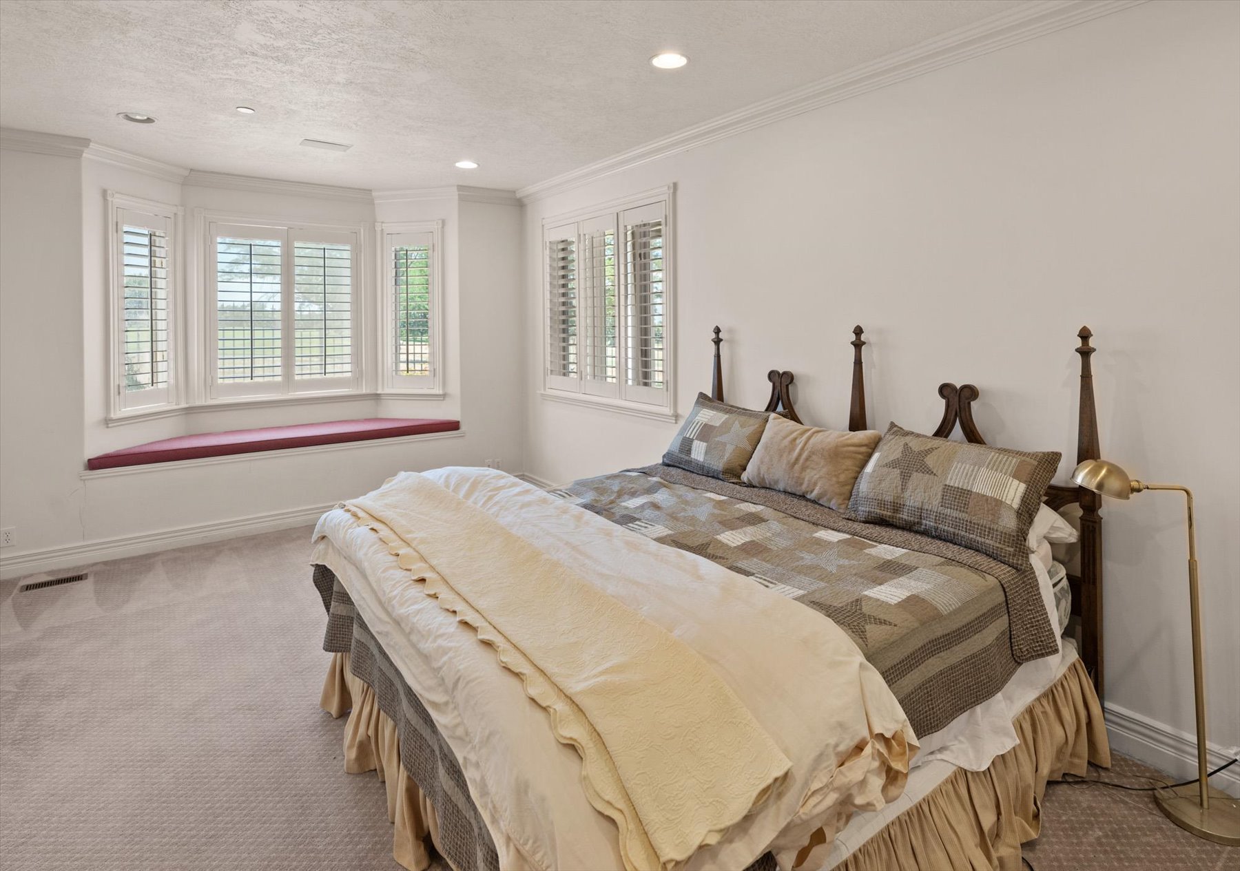 Bay window with a built-in window seat, plantation shutters, recessed lighting, and crown molding