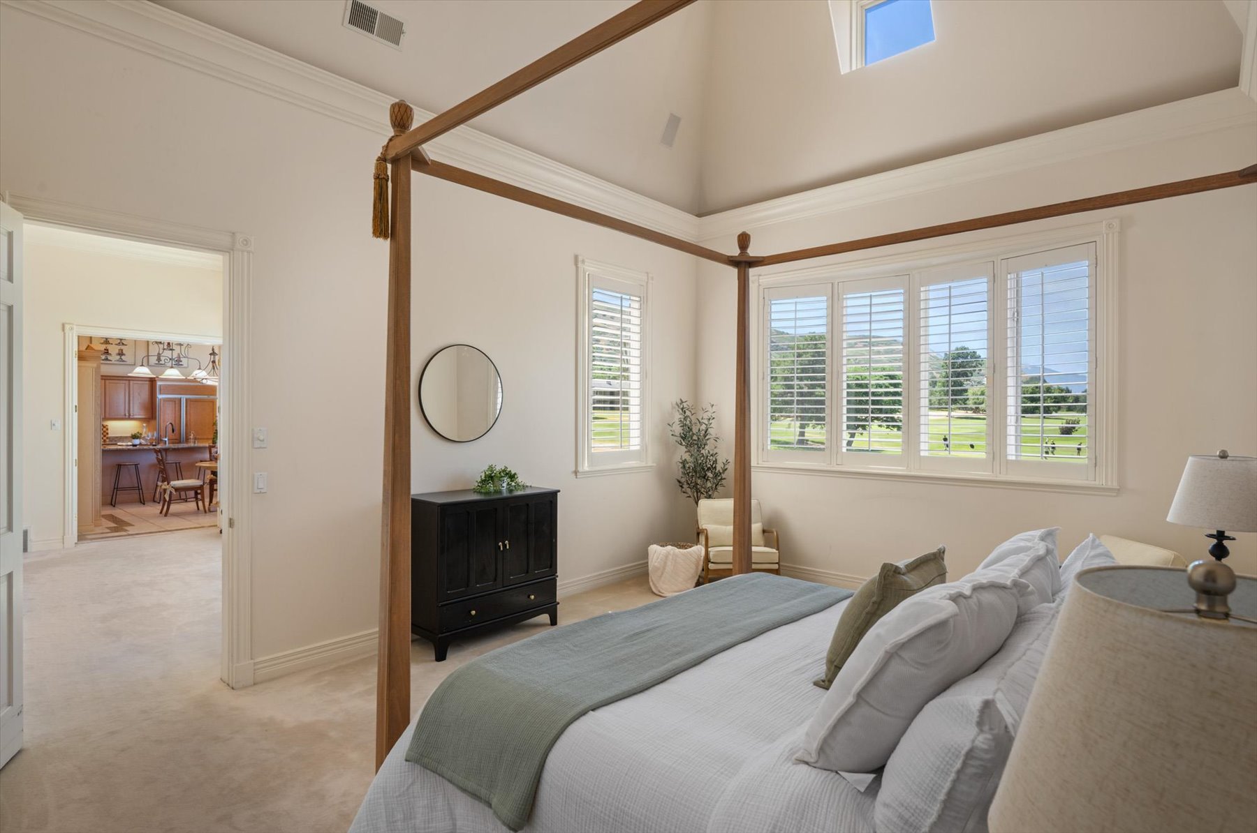 Spacious room featuring vaulted ceilings, a large window array with plantation shutters, and plush carpet flooring