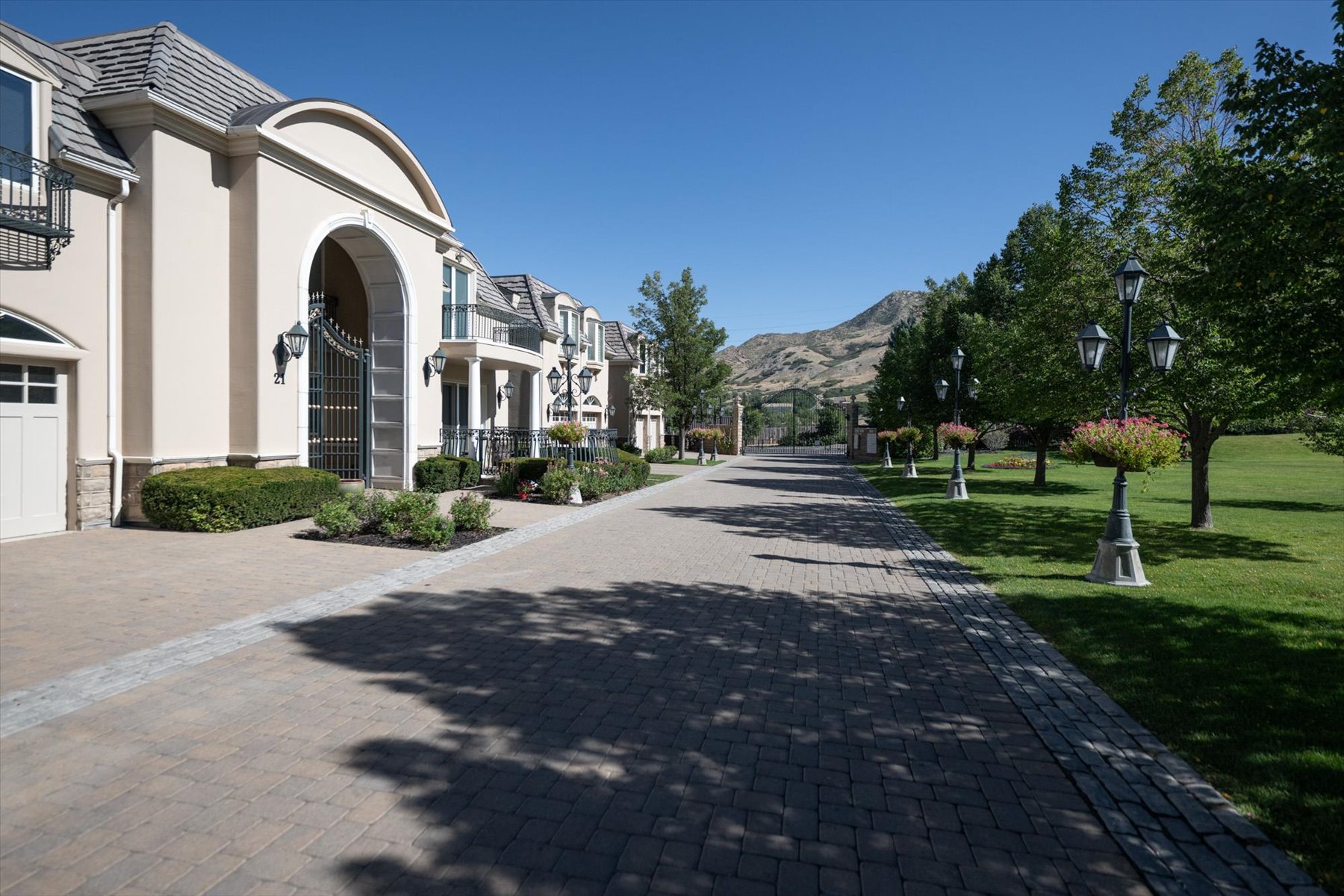Paved driveway bordered by mature trees and manicured lawn