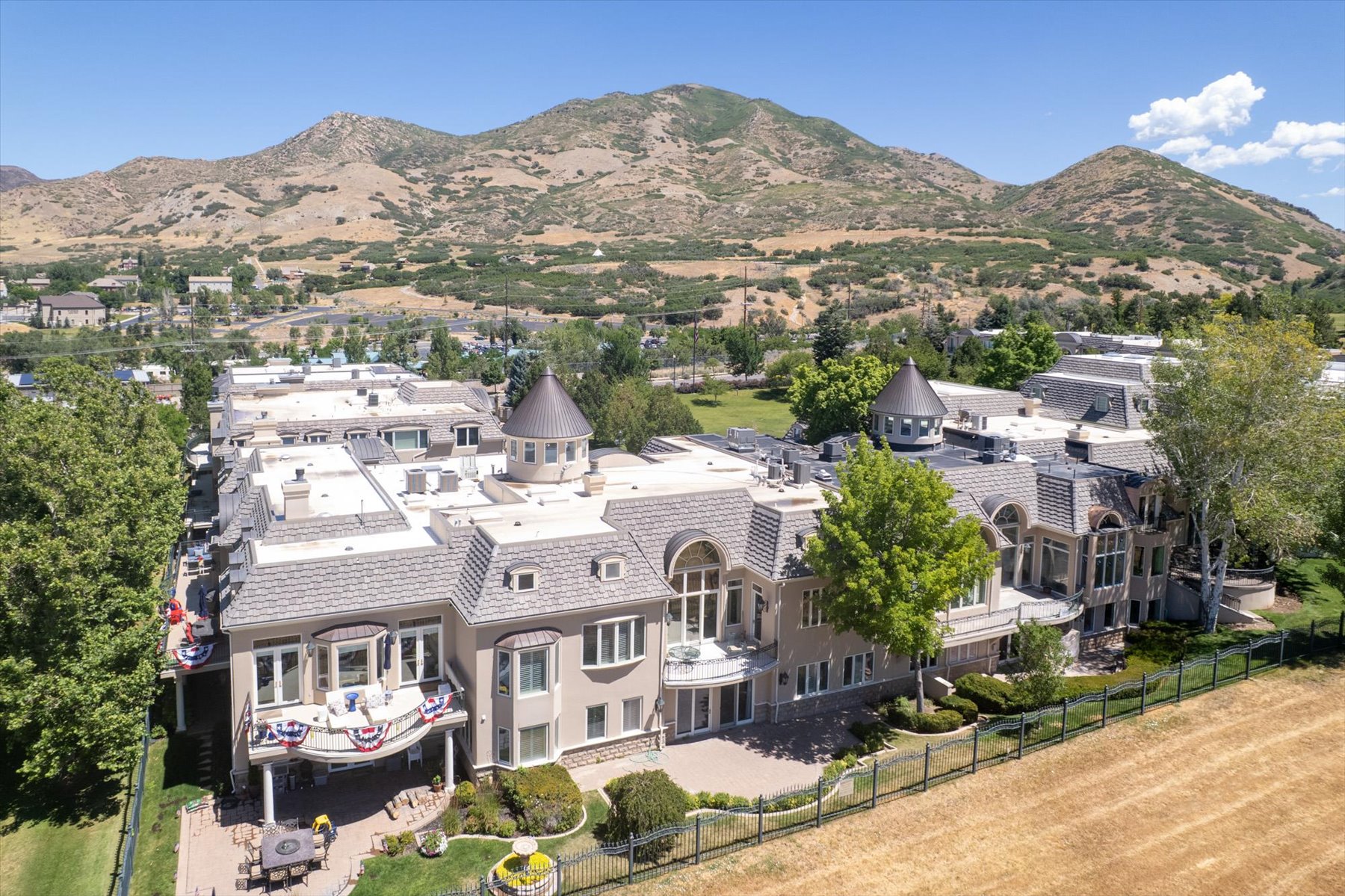 Expansive estate featuring multiple turrets, a multi-story balcony, and an outdoor patio with built-in planters