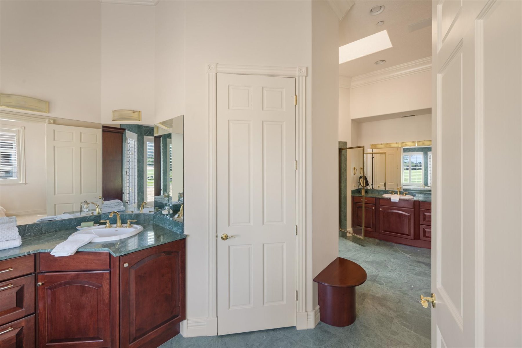 Spacious bathroom featuring two distinct vanity areas, each with a single sink and a green stone countertop