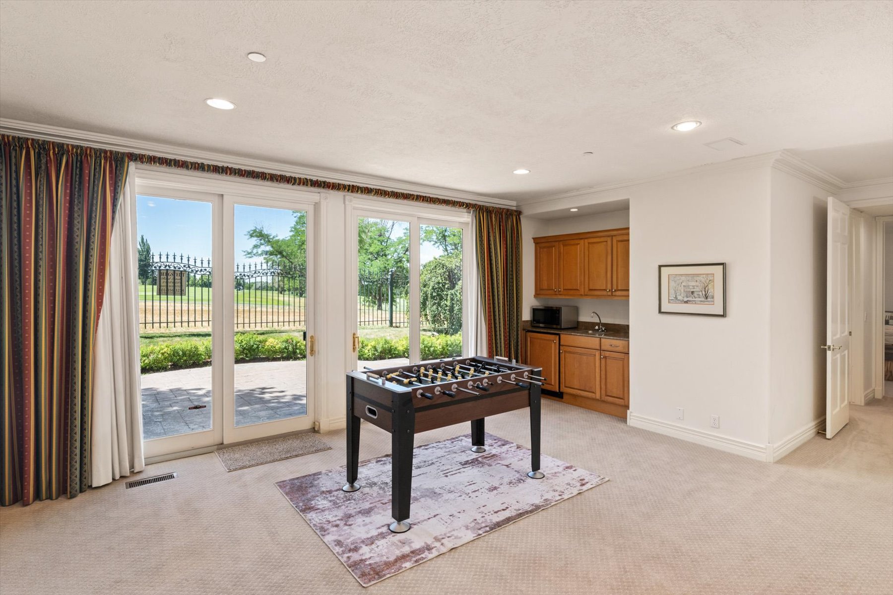 Room featuring glass patio doors in a walk out basement leading to Bonneville Golf Course, a built-in wet bar with wood cabinetry, recessed lighting, and crown molding