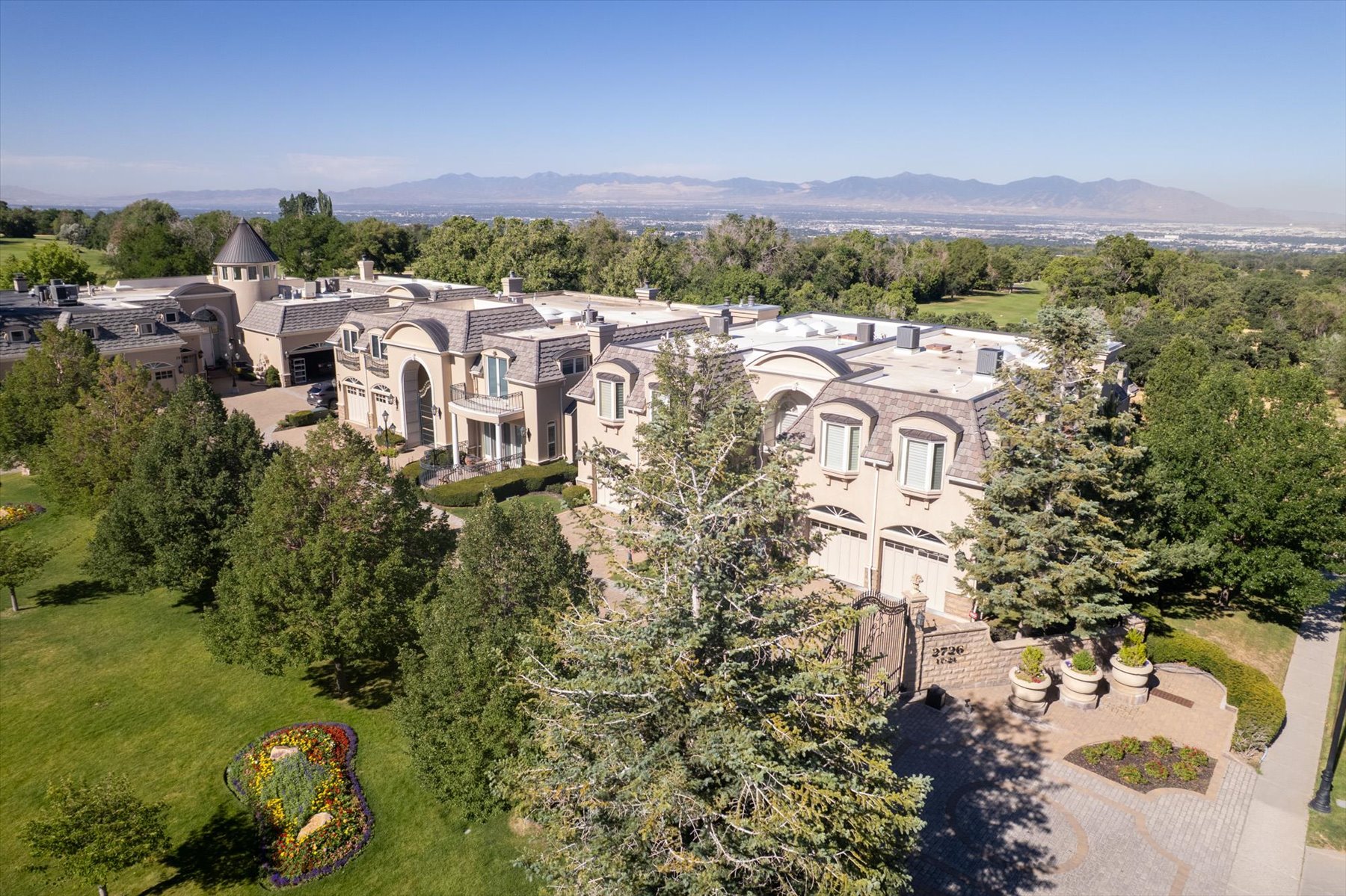 Expansive estate featuring a grand architectural design, multiple garage bays, and a turret structure