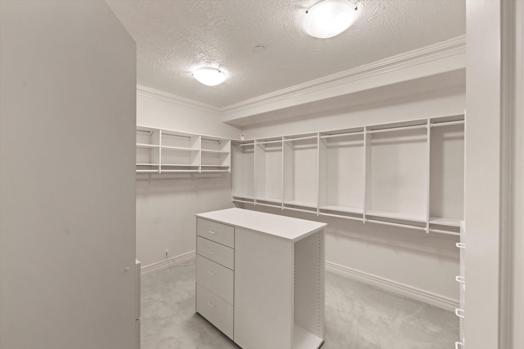 Customizable closet system with a central dresser island featuring multiple drawers and open shelving