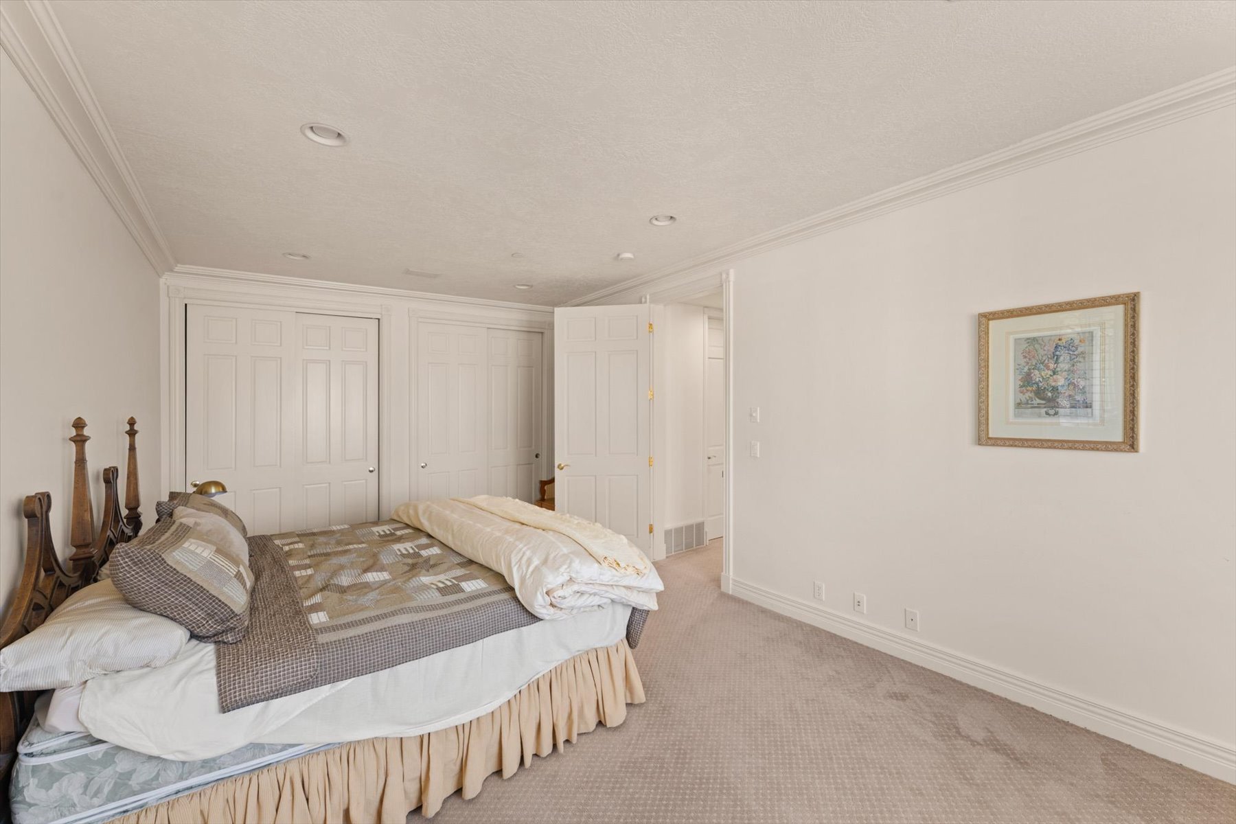Carpeted bedroom featuring white walls, crown molding, recessed lighting, and white bi-fold closet doors