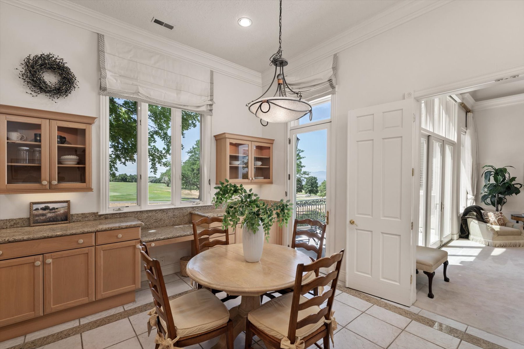 Dining area with large windows, light wood cabinetry, granite countertops, and tile flooring