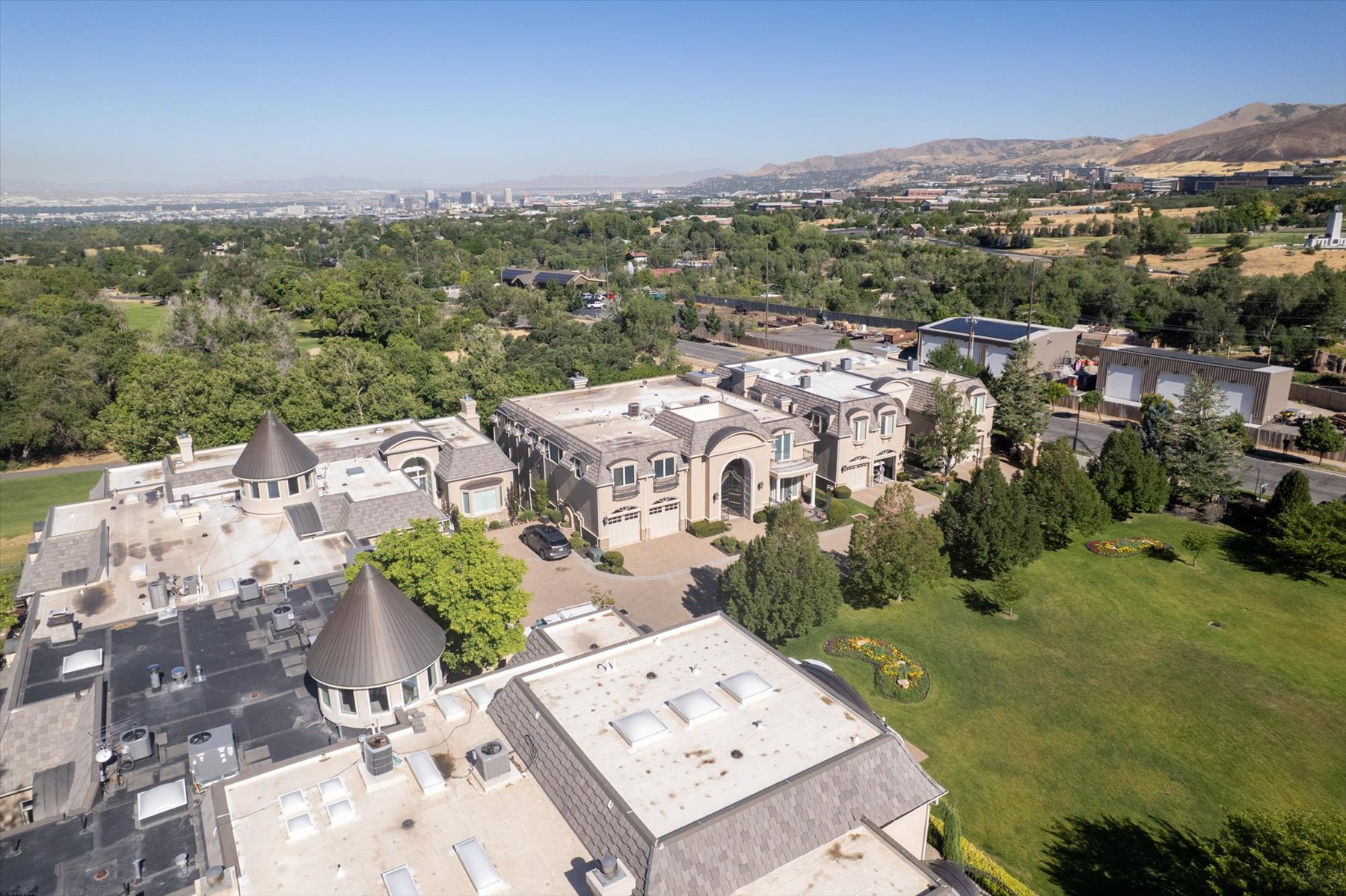 Expansive estate featuring multiple structures with arched entryways, extensive green spaces, and a mountainous backdrop