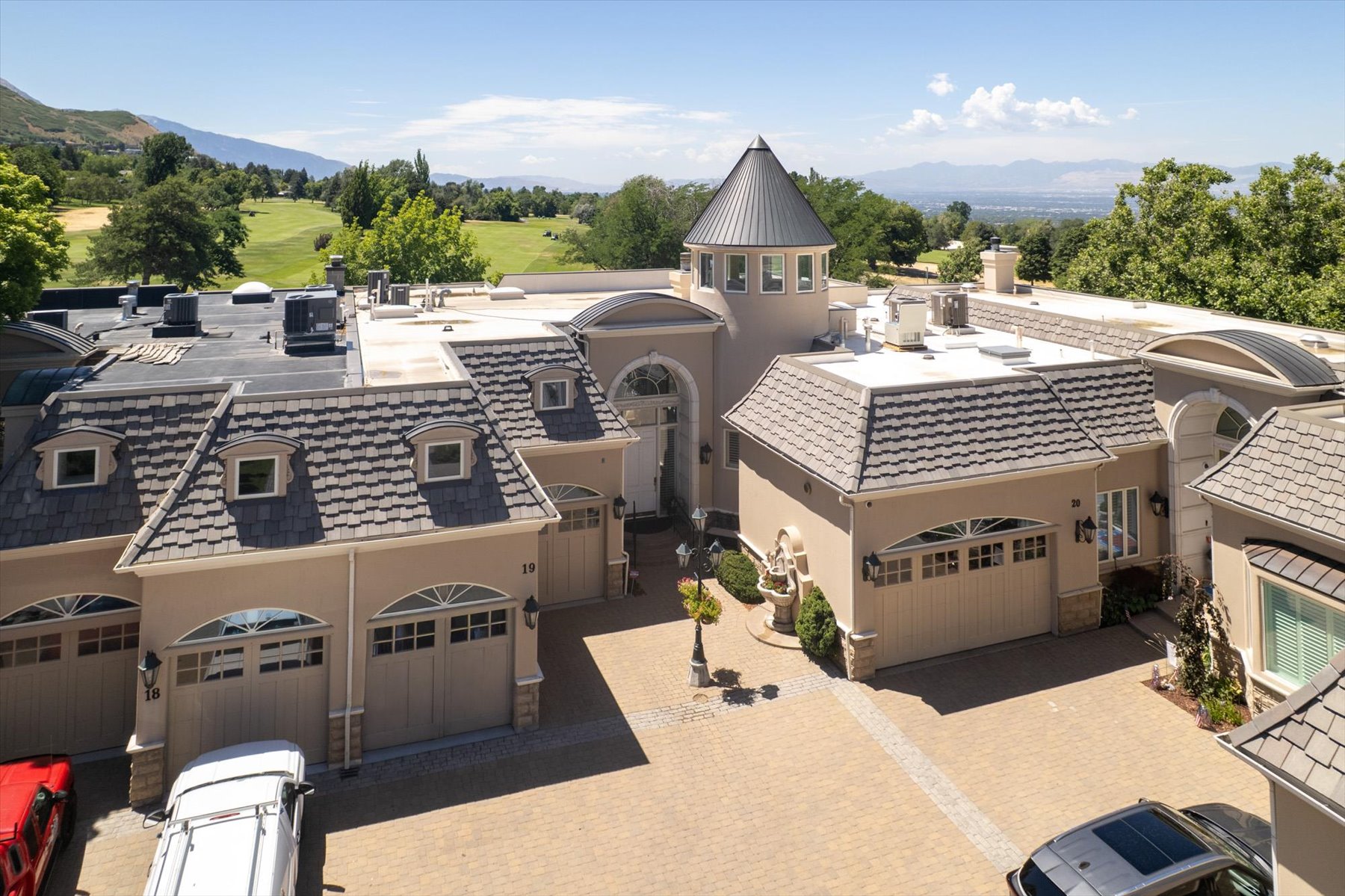 Expansive paver driveway leading to a multi-car garage with arched doors