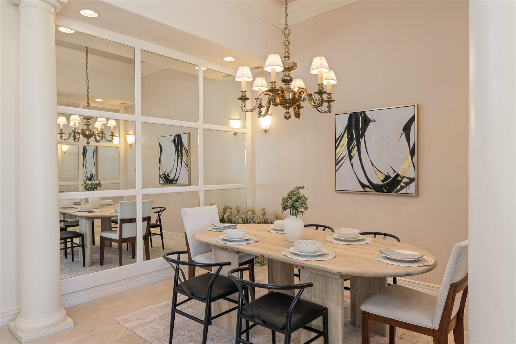 Formal dining area featuring a prominent mirrored wall, a classic brass chandelier, and a decorative wall sconce