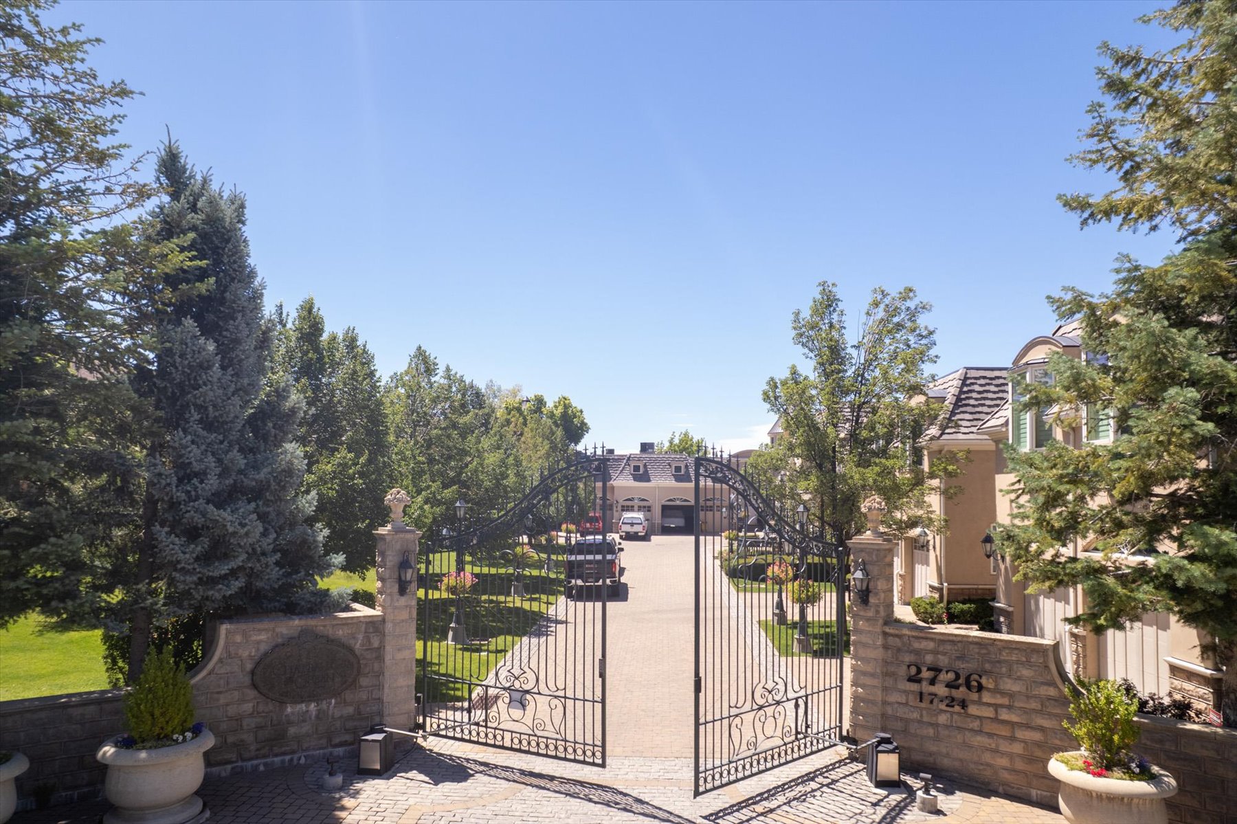 Wrought iron arched entry gate with decorative elements, flanked by stone pillars and retaining walls