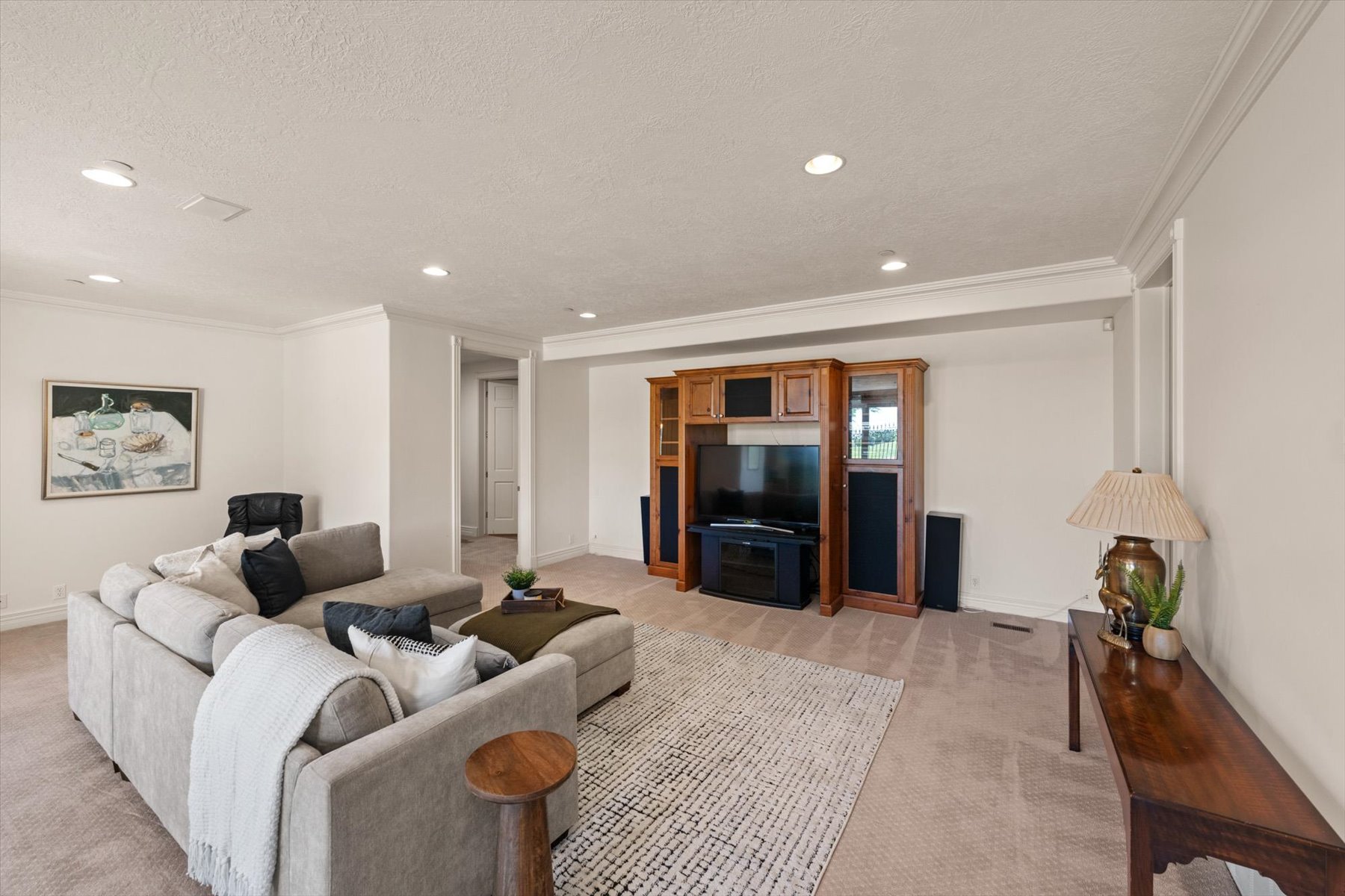 Spacious living area featuring recessed lighting, crown molding, light-colored carpeting, an entertainment center, and a neutral wall color