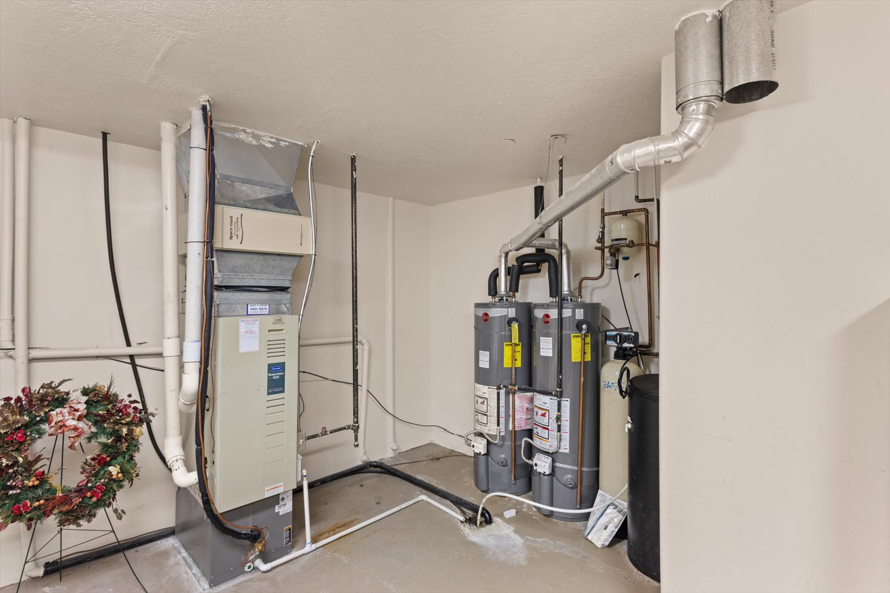 Utility area featuring a forced air furnace, two water heaters, and a water softener system